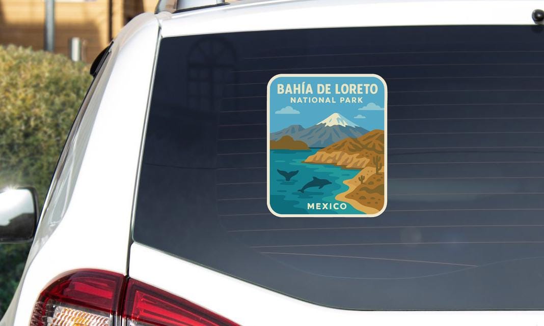 A sticker on the rear window of a car, depicting a scenic landscape with mountains, a lake, and a beach.