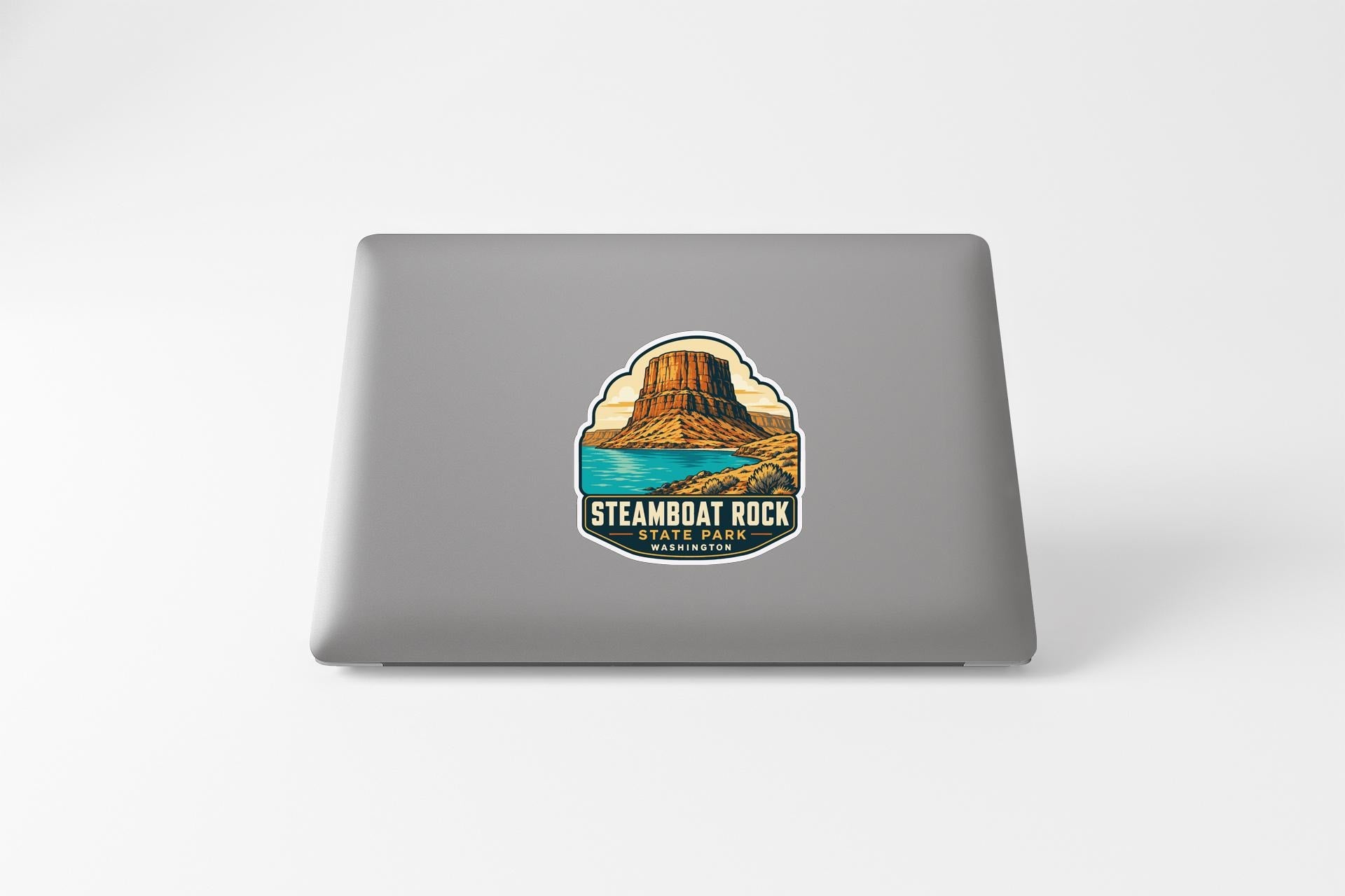 a sticker or decal on the back of a laptop, depicting a scenic landscape with a mountain and a body of water.