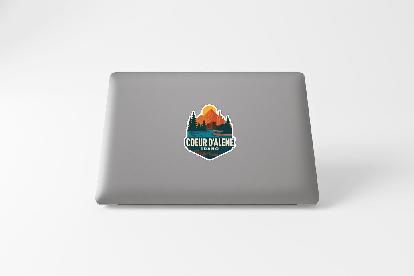a sticker on the back of a laptop with a mountain landscape and the text "COEUR D'ALENE IDAO".