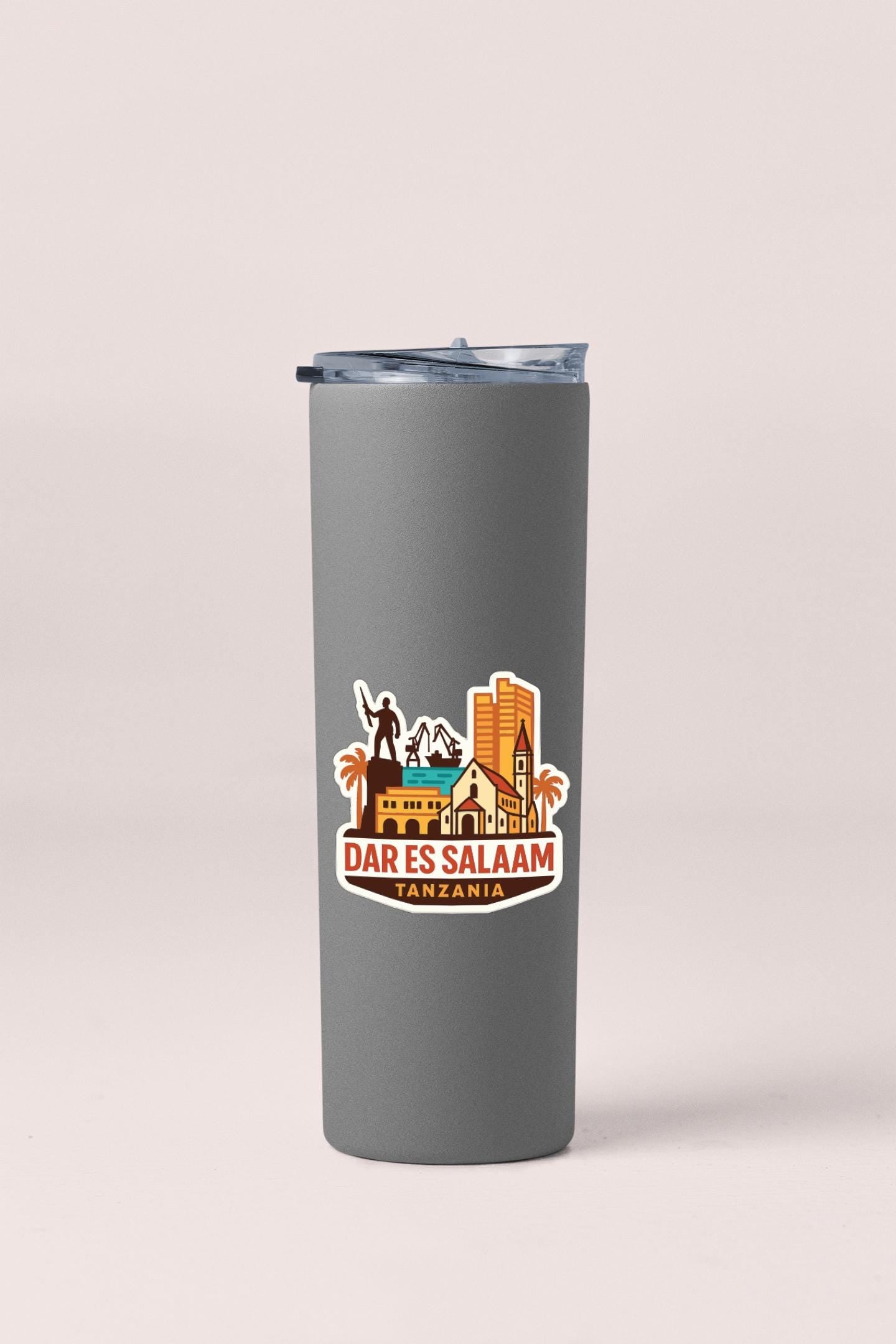 A gray tumbler with a logo depicting a city skyline and the text "DAR ES SALAAM TANZANIA" printed on it.