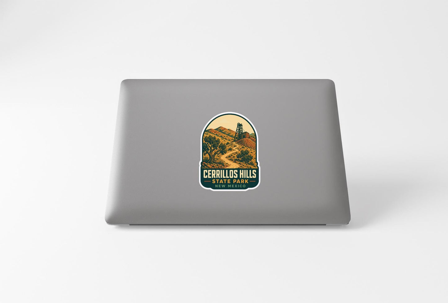 a sticker with a scenic landscape of hills and a lighthouse, placed on the back of a laptop computer.