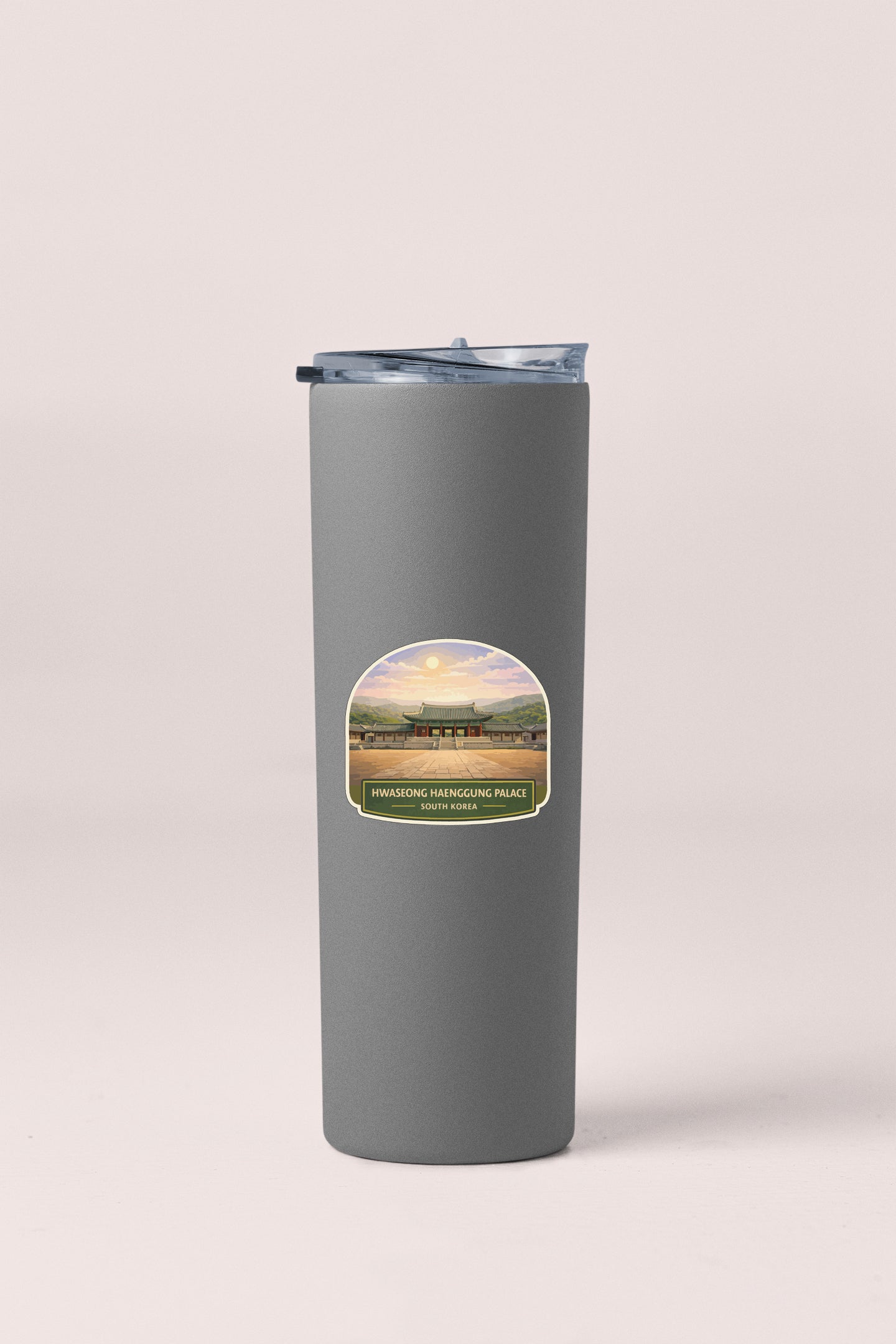 A gray insulated tumbler with a label depicting a scenic landscape.