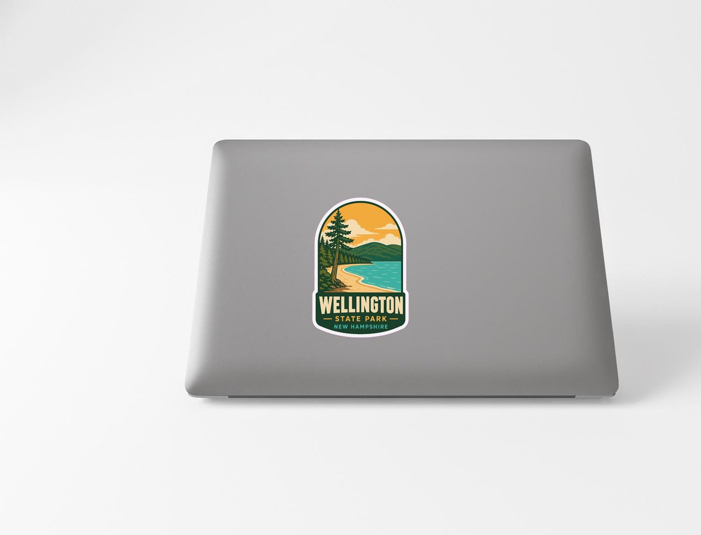 A sticker on the back of a laptop that says "Wellington" and "New Zealand Park", along with a scenic landscape of a beach and mountains.