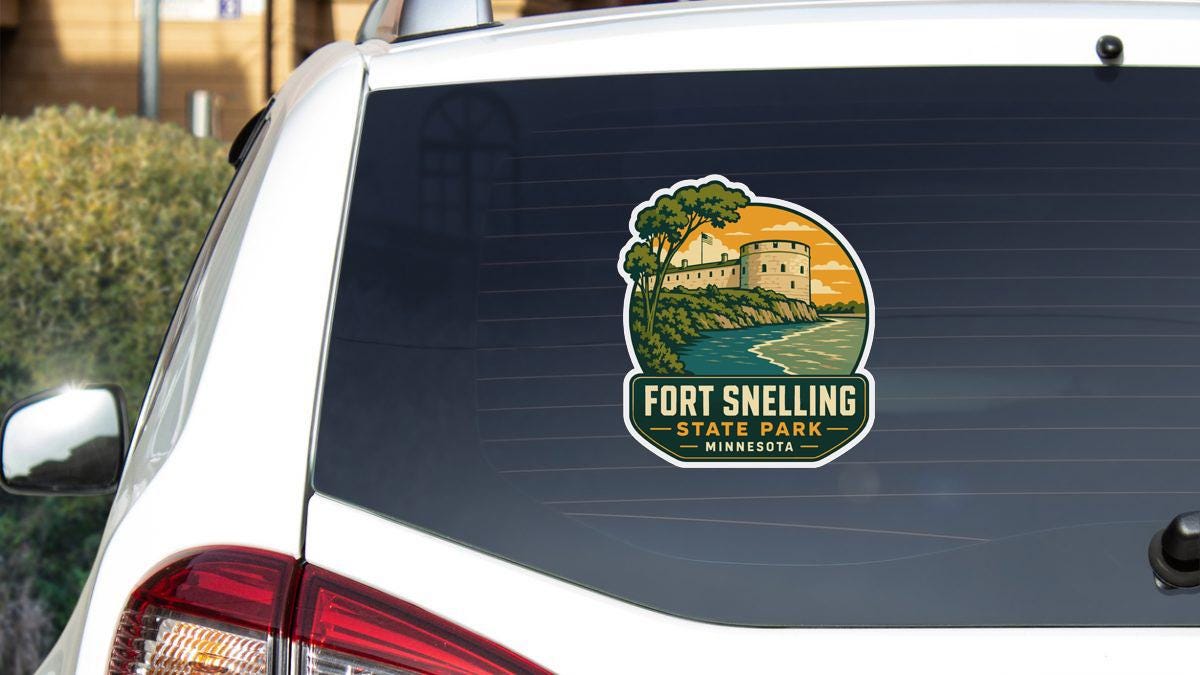 A sticker on the rear window of a white vehicle, depicting a scenic landscape with a castle or fort in the background.