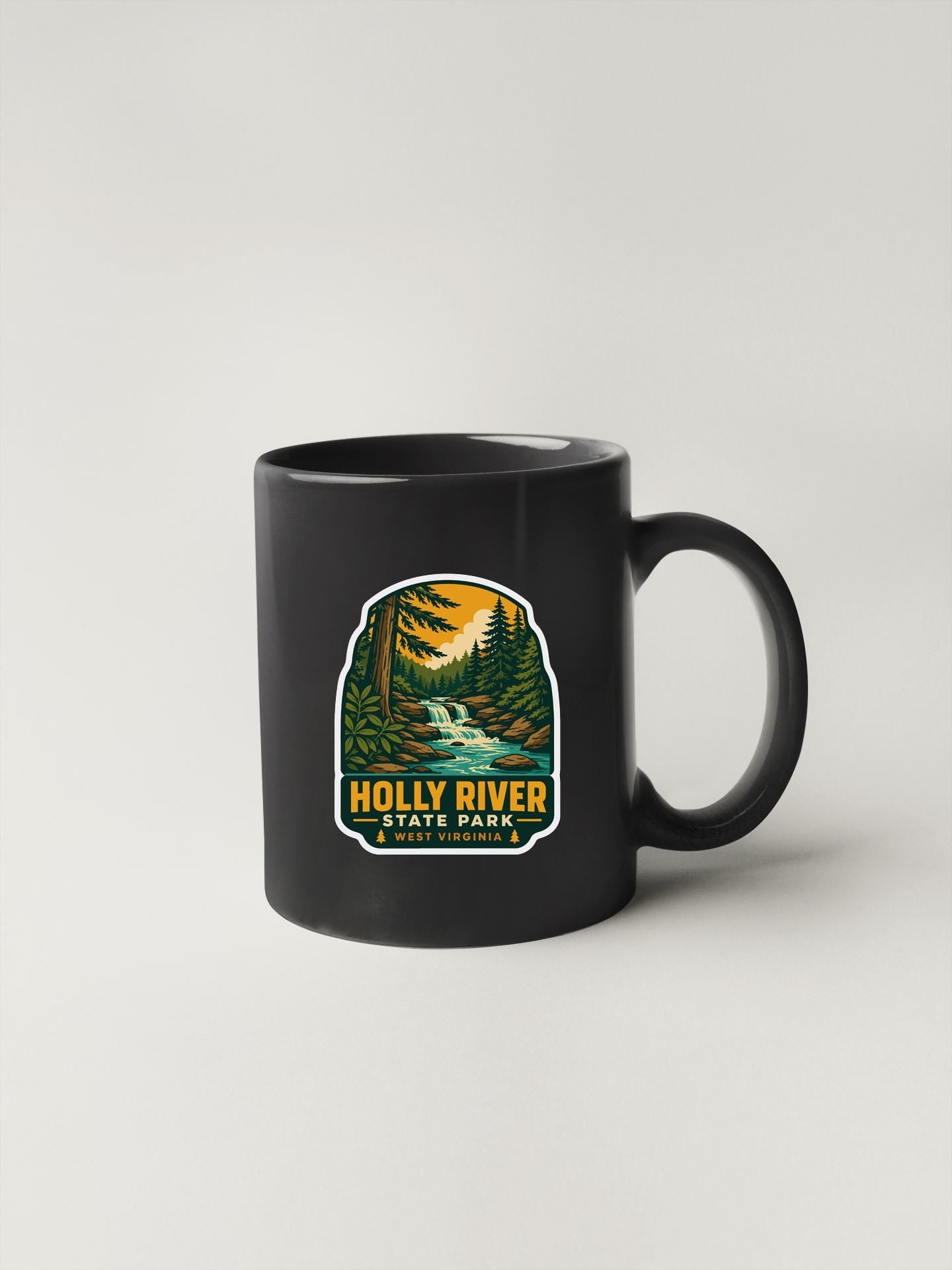 A black coffee mug with a graphic design depicting a scenic landscape featuring a river, waterfall, and forest.