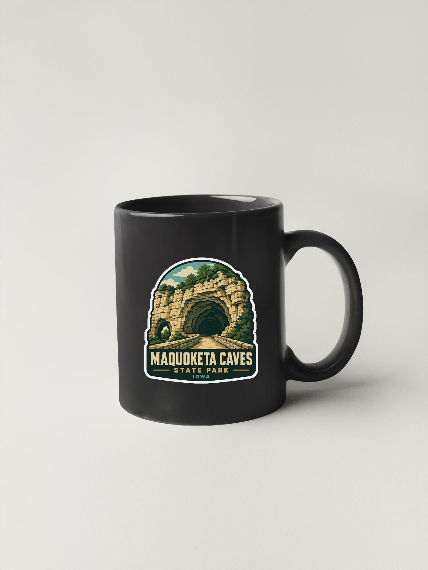 A black coffee mug with a graphic design depicting the Maquoketa Caves in Iowa State Park.