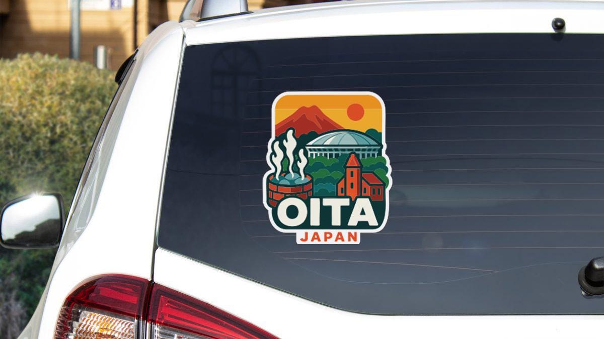 A sticker on the rear window of a car that features an illustration of a cityscape with a mountain in the background and the word "OITA" prominently displayed.
