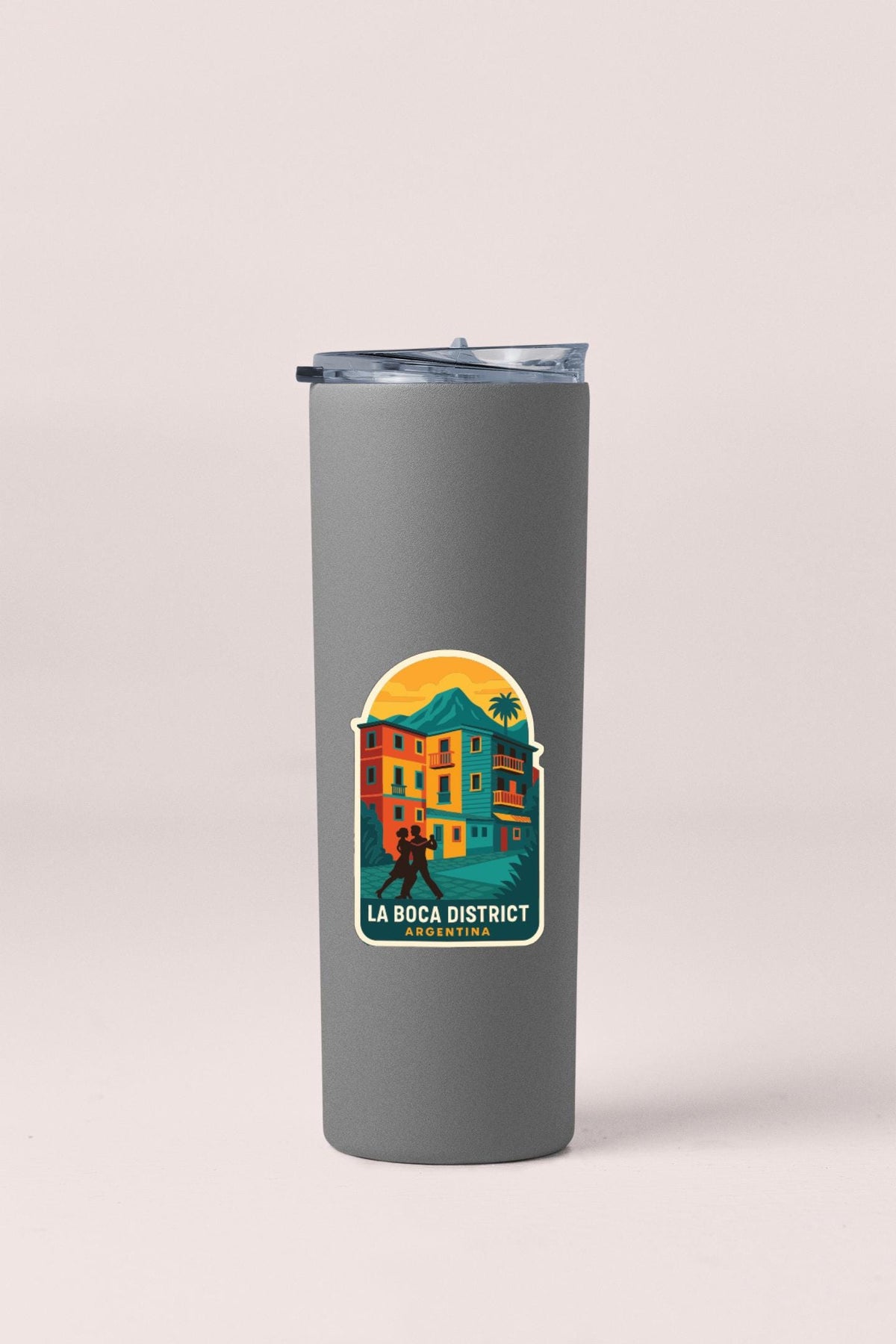 A gray insulated tumbler with a sticker depicting a colorful illustration of a building and a person.