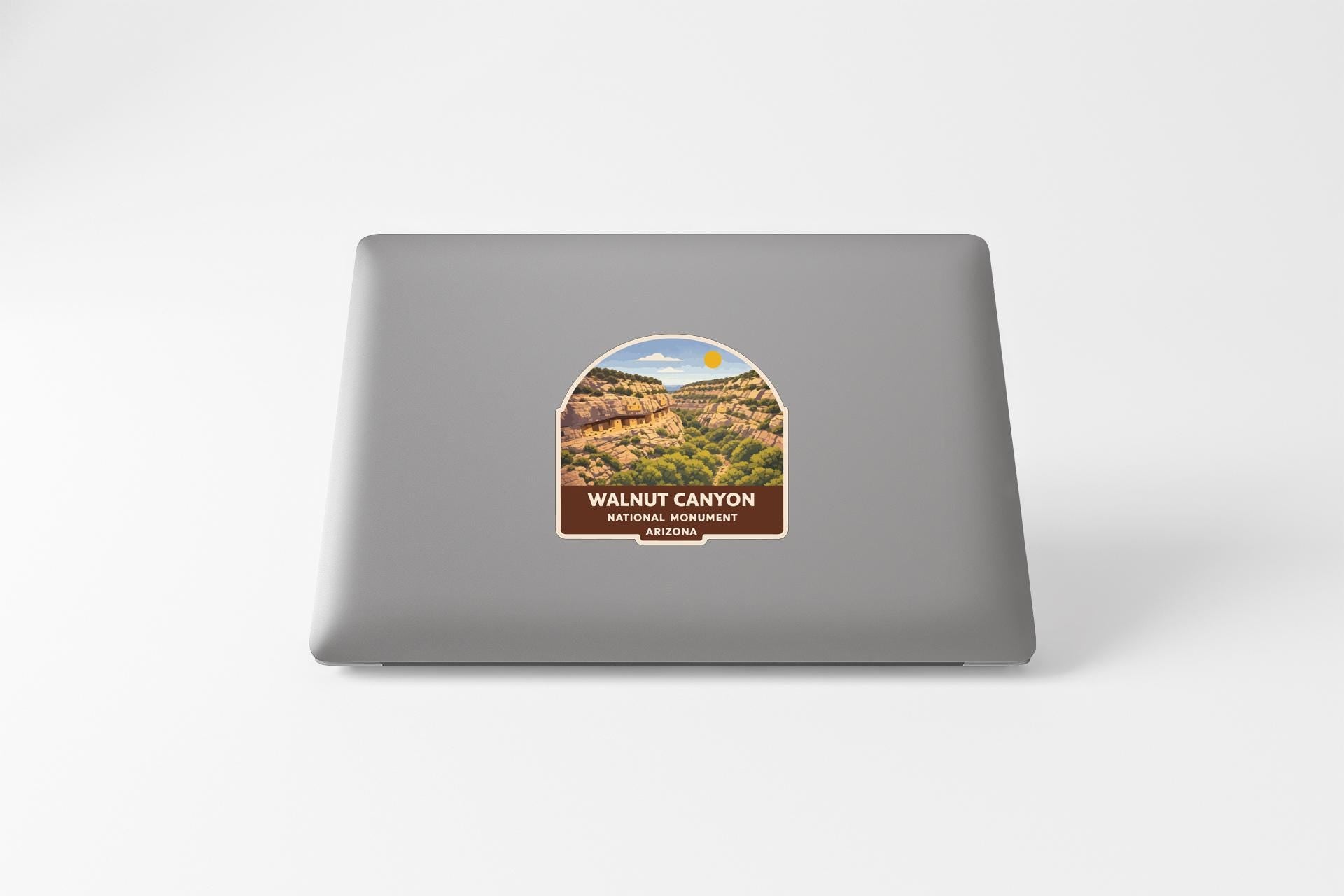 a sticker on the back of a laptop that displays a scenic image of a canyon, with the text "WALNUT CANYON NATIONAL PARK WALNUTS, COLORADO" printed on it.