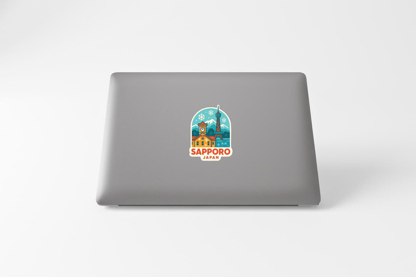 a sticker with a cityscape and the text "SAPPORO JAPAN" on the back of a laptop.