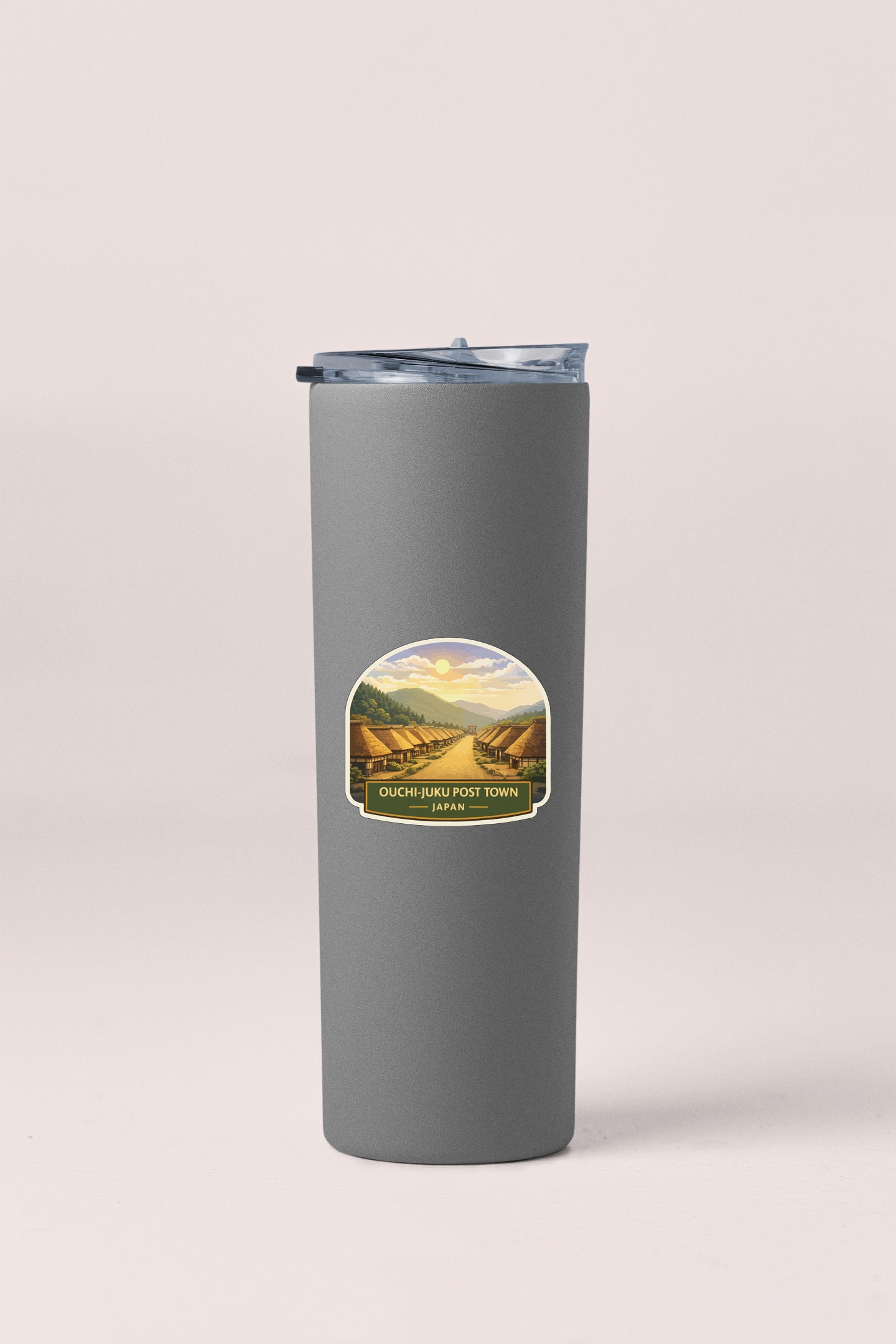 A gray insulated tumbler with a label depicting a scenic landscape.