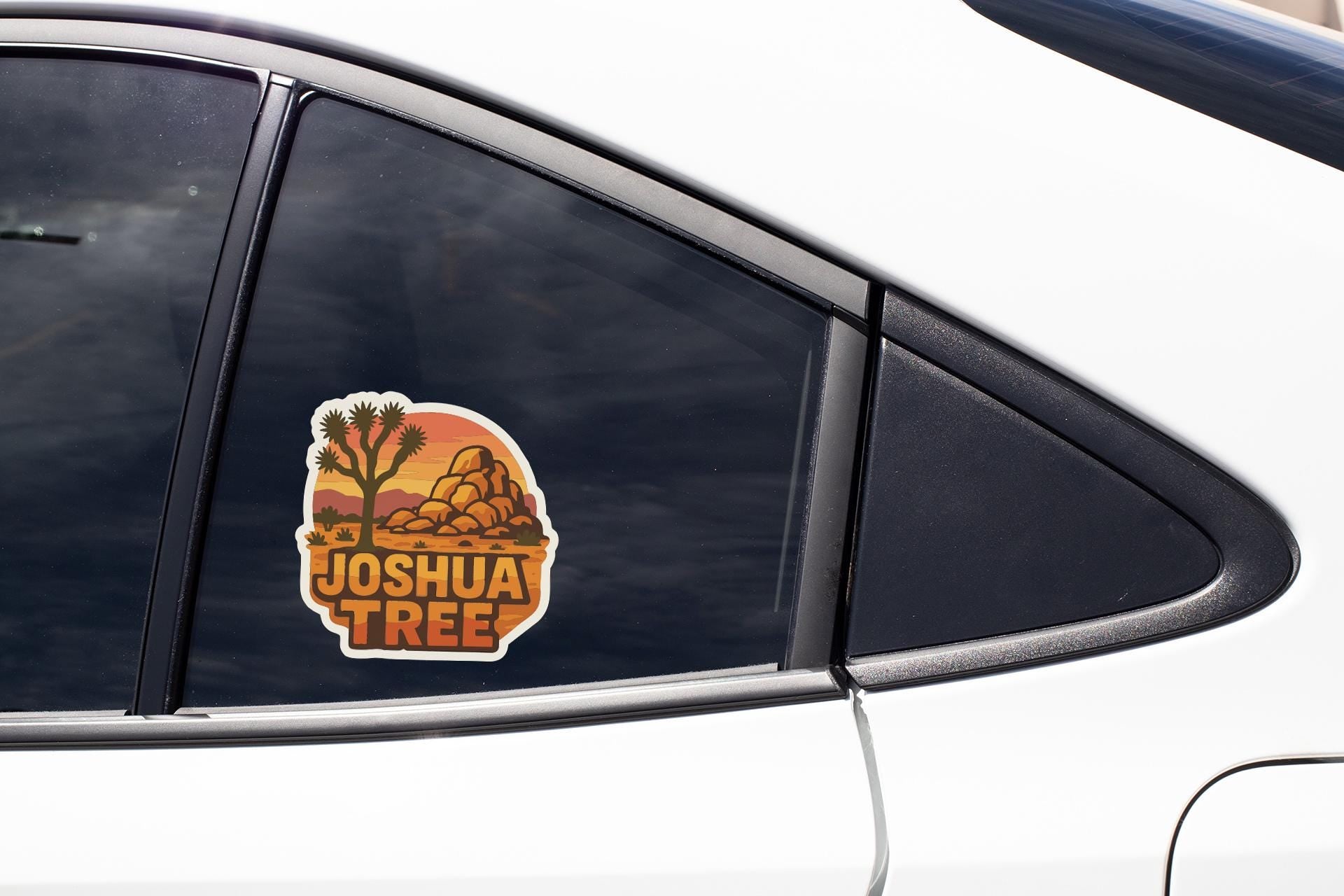A car window with a sticker featuring a desert landscape and the text "JOSHUA TREE".