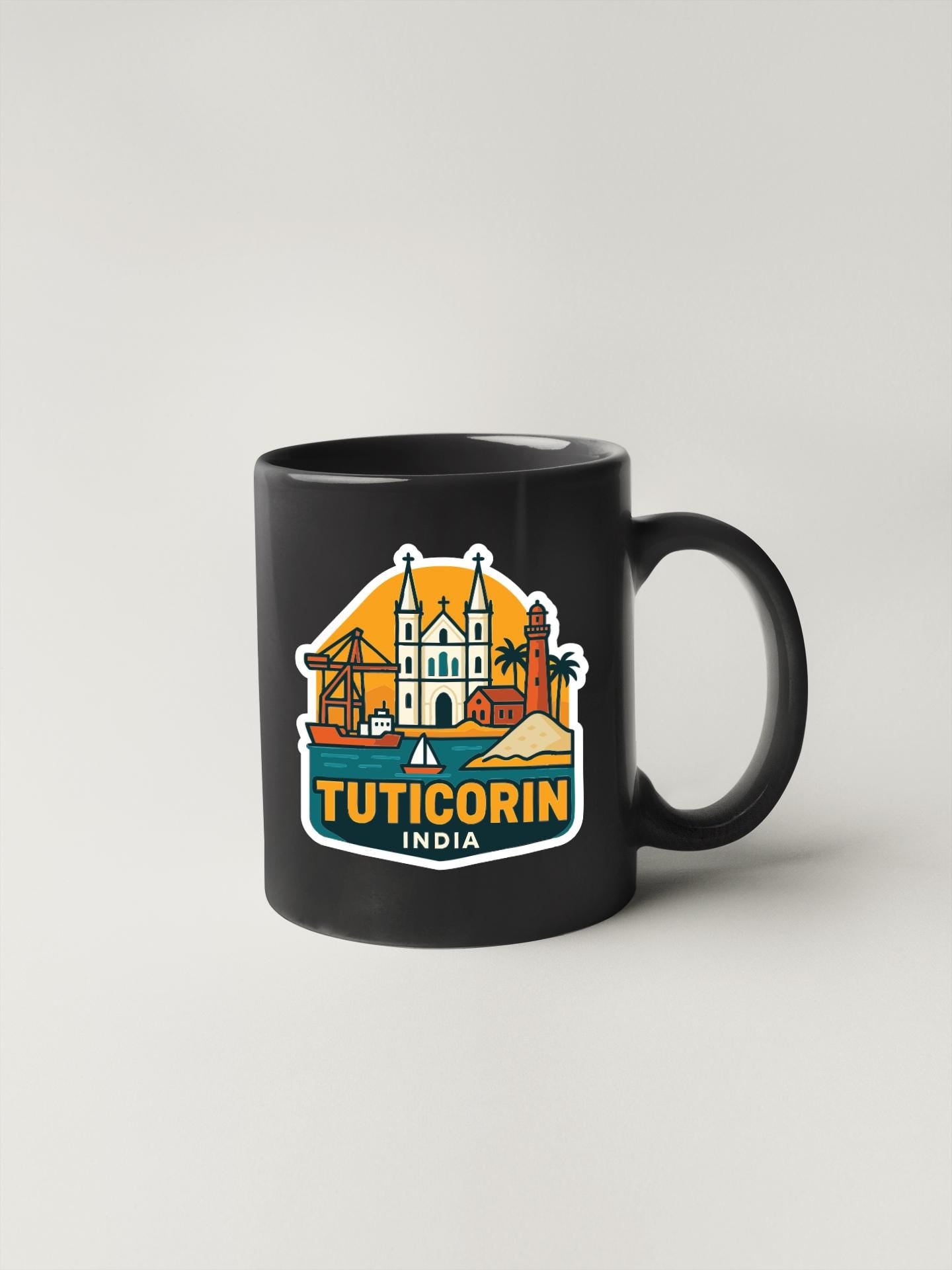 A black coffee mug with a colorful graphic design depicting landmarks and buildings in the city of Tuticorin, India.