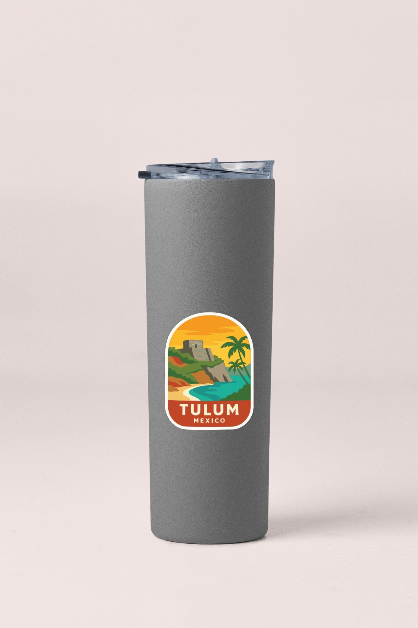 A gray insulated tumbler with a sticker depicting a tropical landscape and the text "TULUM MEXICO" printed on it.