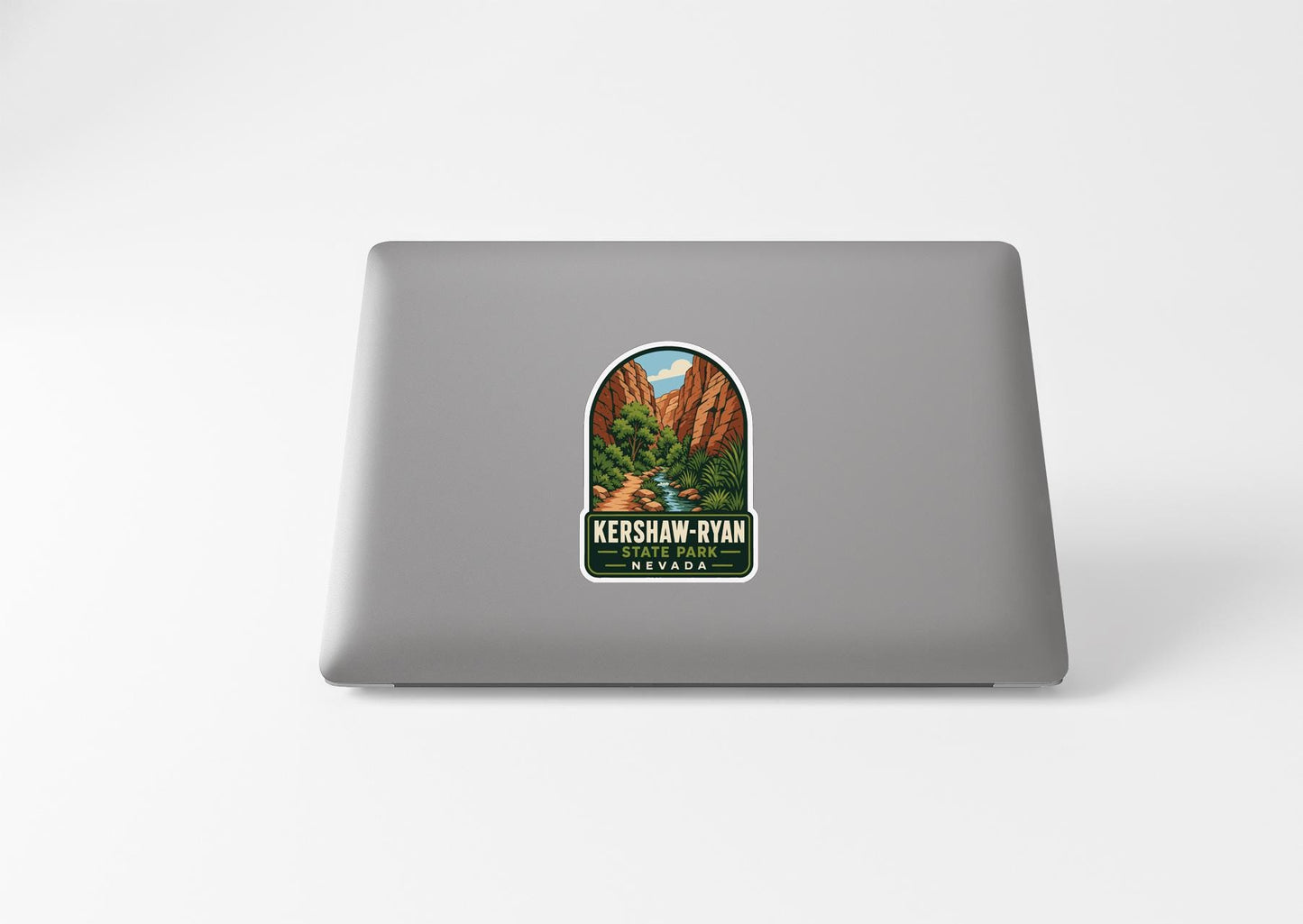 A sticker on the back of a laptop, depicting a scenic landscape with mountains and a river.