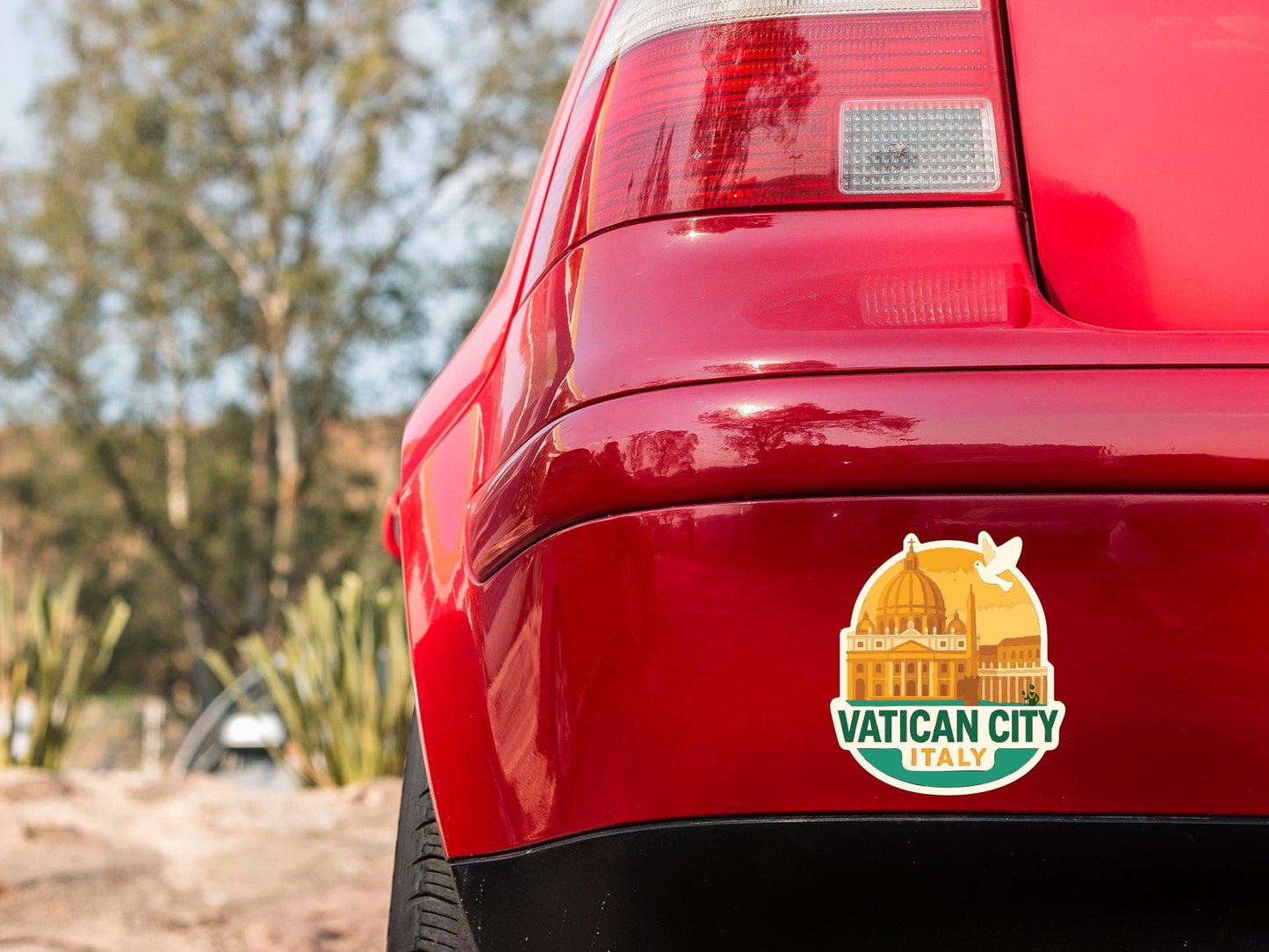 the rear end of a red car with a sticker on the trunk that says "VATICAN CITY ITALY".