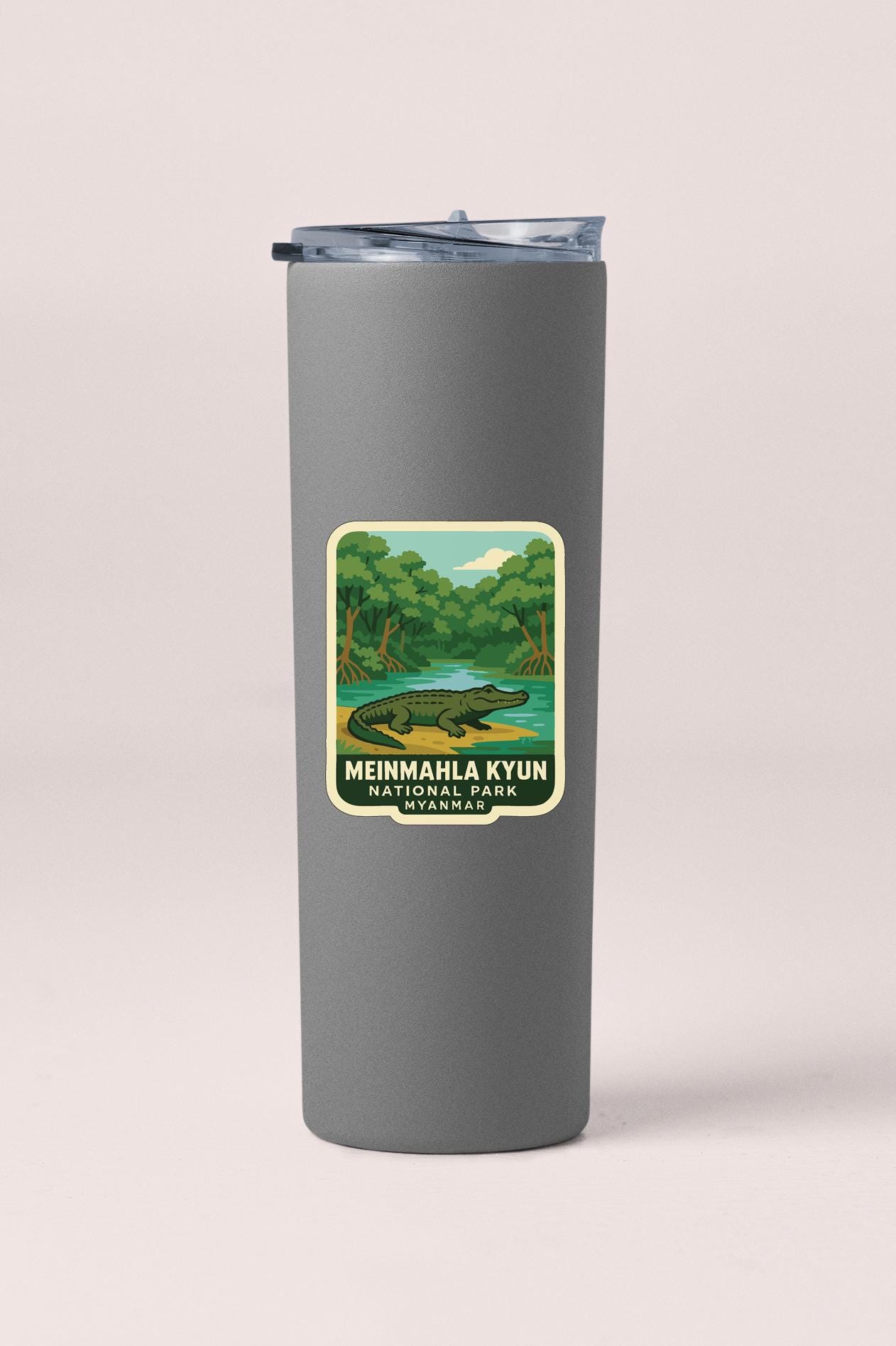 A gray insulated tumbler with a label depicting a crocodile and a river, along with the text "MEINMAHLA KYUN NATIONAL PARK MYANMAR".