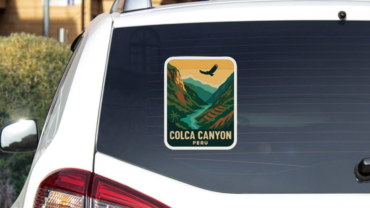 A sticker on the rear window of a white car, depicting a scenic mountain landscape with a bird in flight.