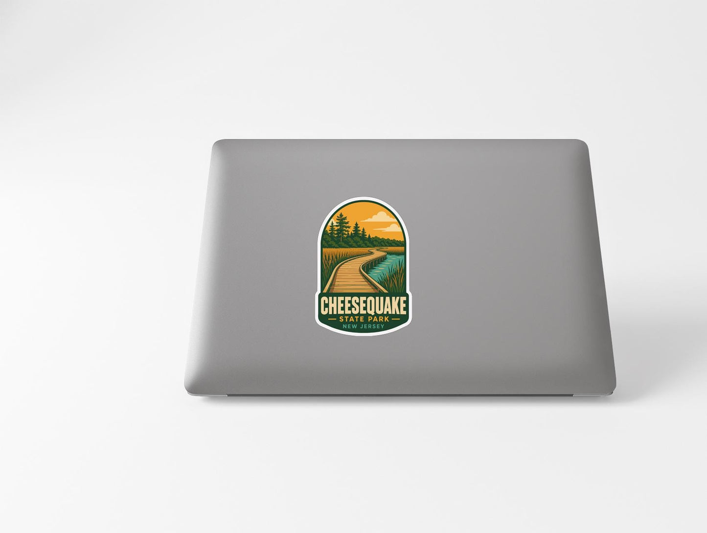 a sticker with a scenic landscape and the text "CHESEAQUACK" on a laptop.