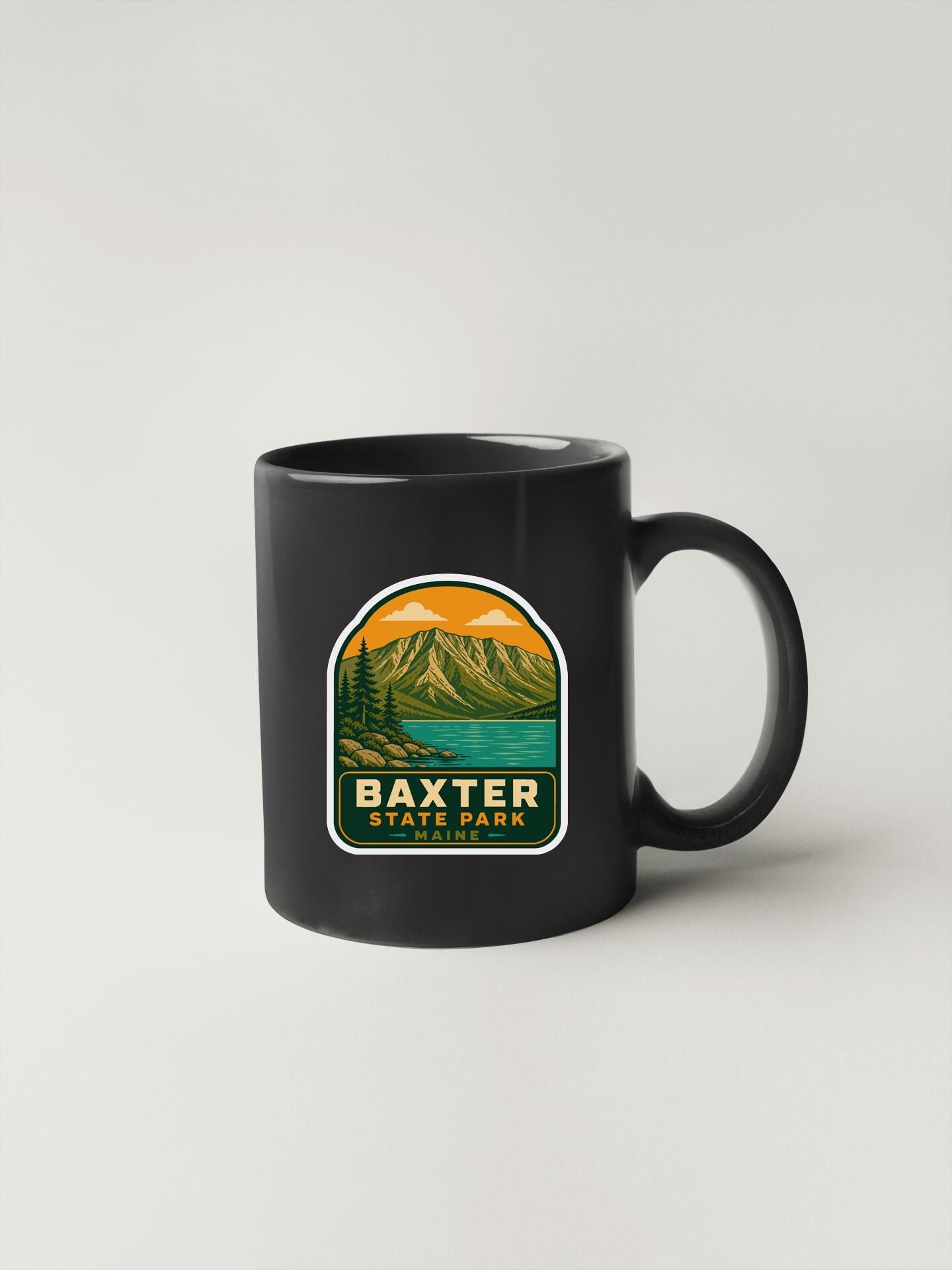 A black coffee mug with a graphic design depicting a mountain landscape and the text "BAXTER STATE PARK" printed on it.