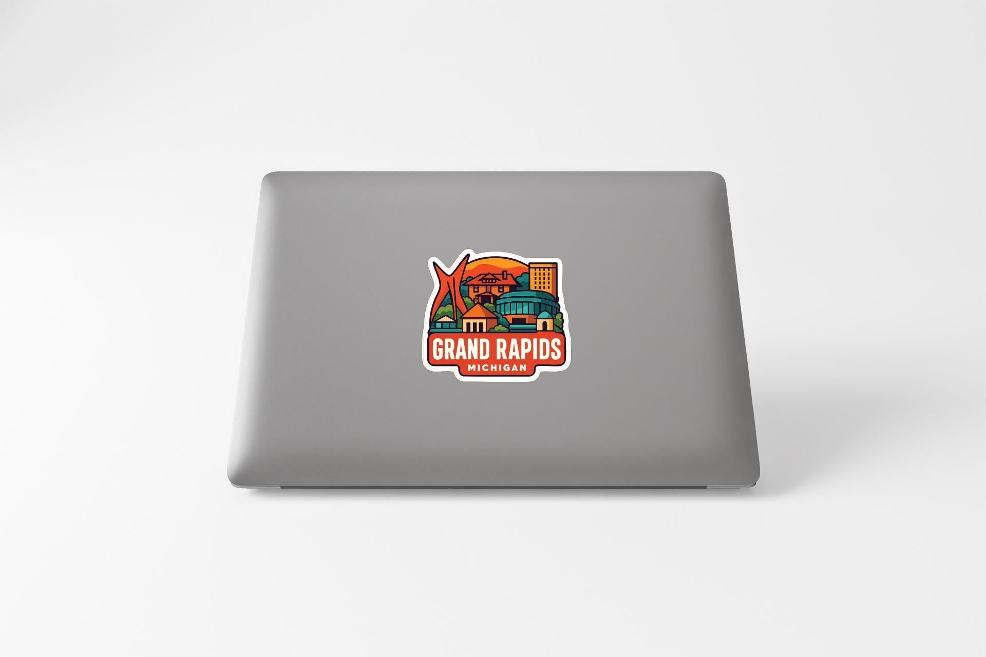 A sticker on the back of a laptop displaying the text "GRAND RAPIDS MICHIGAN" along with an illustration of a cityscape.