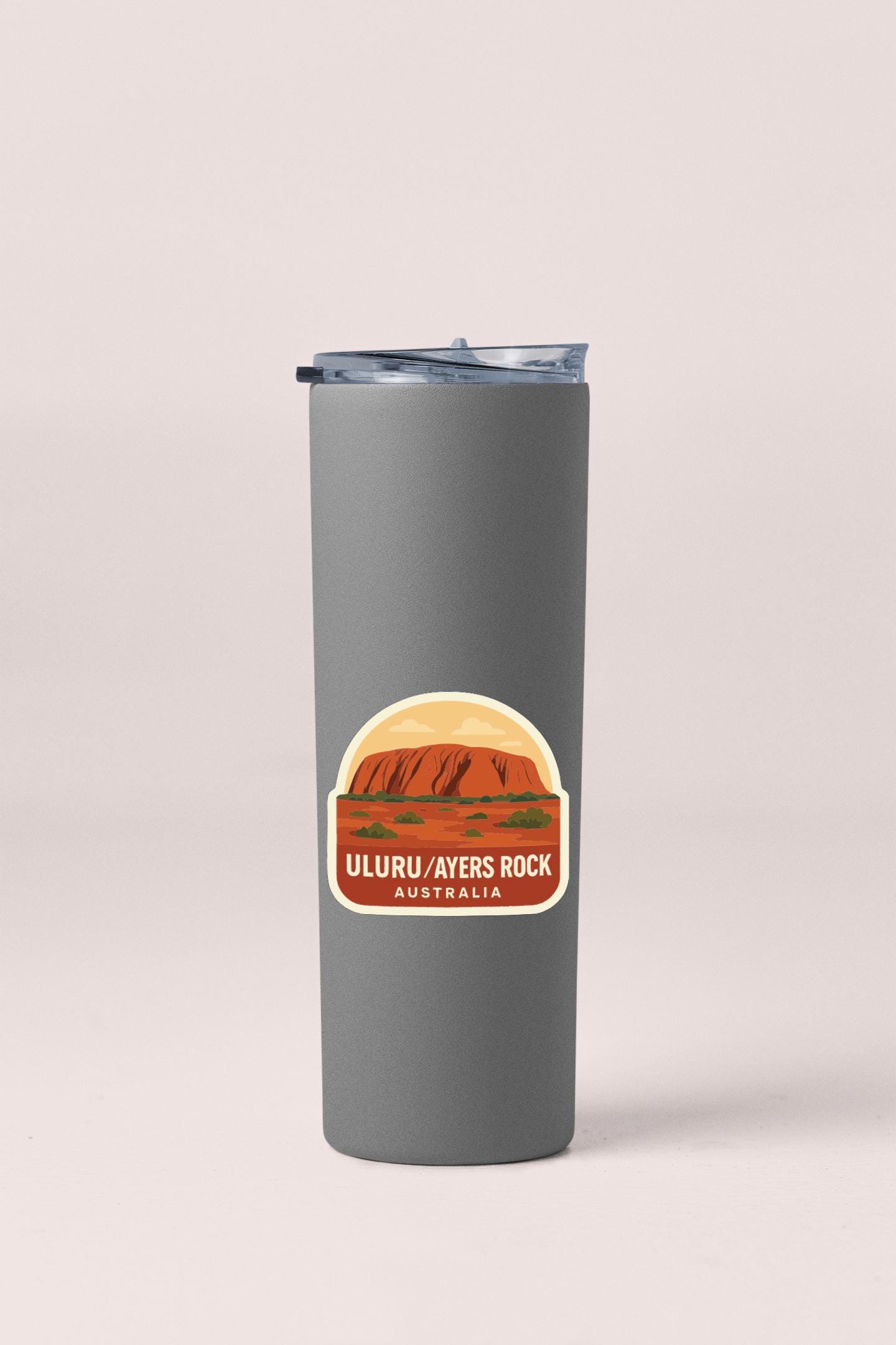A gray insulated tumbler with a sticker depicting Uluru-Ayers Rock in Australia.