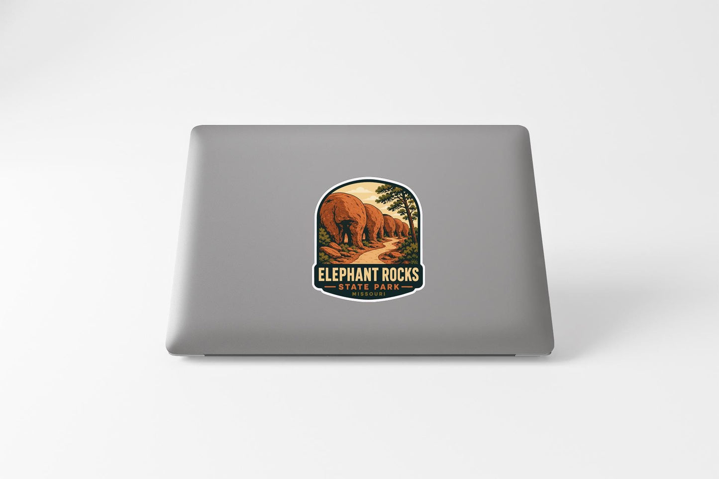 a sticker or decal on the back of a laptop, depicting a scenic landscape with a road leading through a forested area.