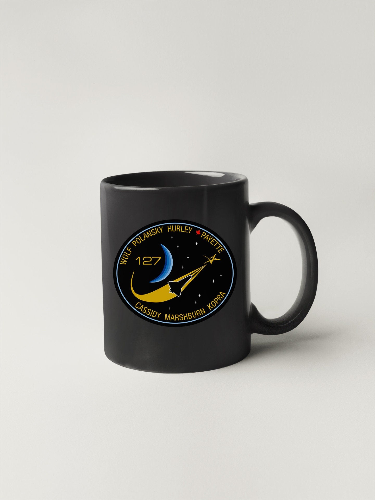 a black coffee mug with a nasa emblem on it