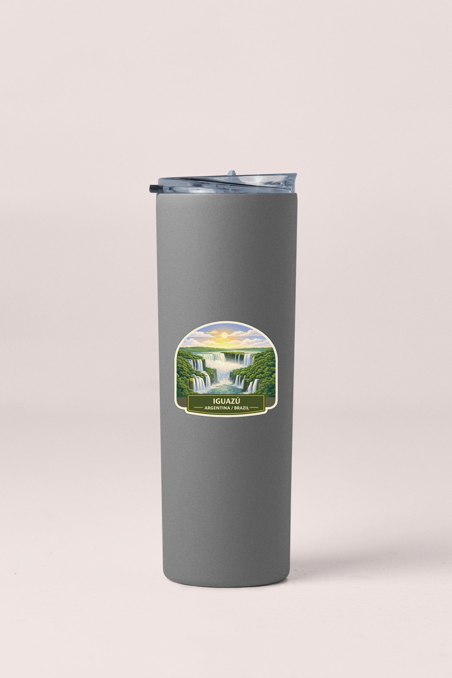 A gray insulated tumbler with a label depicting a scenic waterfall landscape.