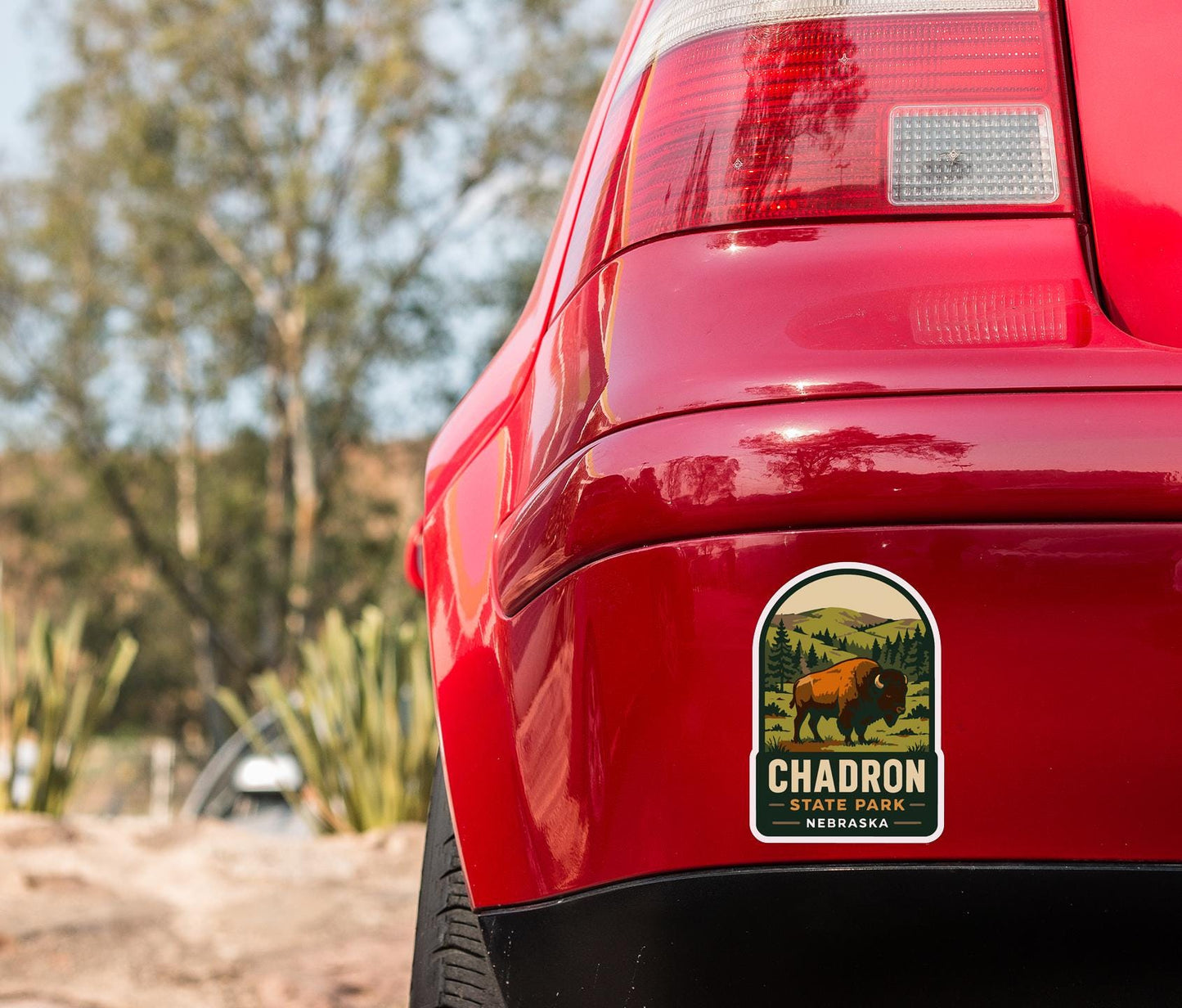 the rear end of a red car with a sticker on the back window that reads "Chadron State Park, Nebraska".