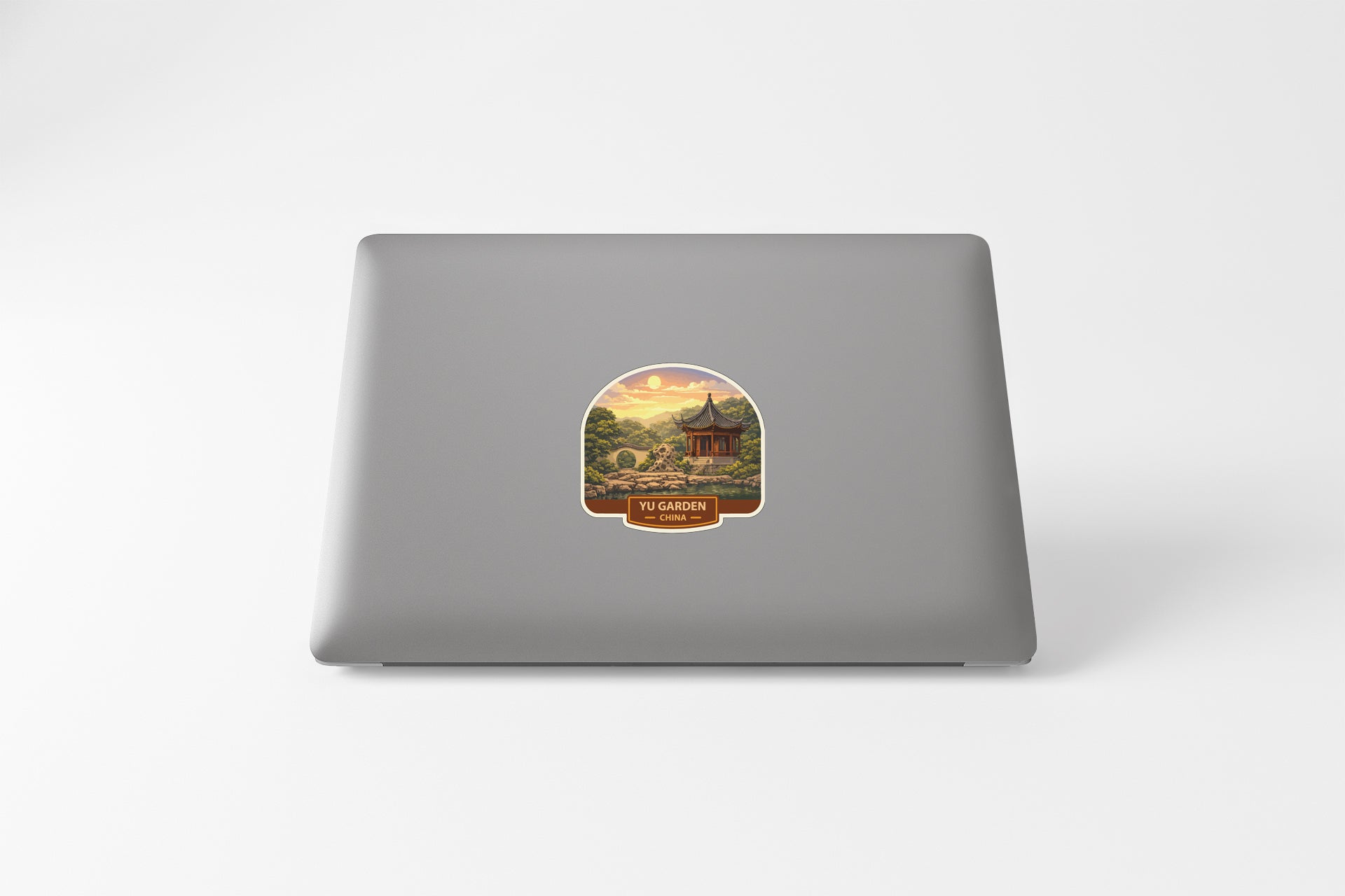 a sticker on the back of a laptop, depicting a scenic landscape with a temple in the background.