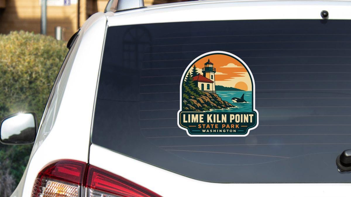 a sticker on the rear window of a white vehicle, depicting a lighthouse and a coastal scene.