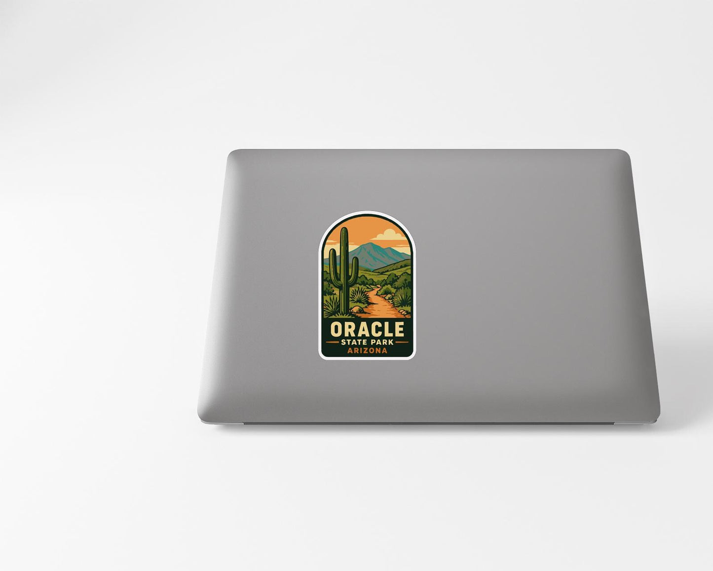 A sticker on the back of a laptop, depicting a desert landscape with mountains and cacti.