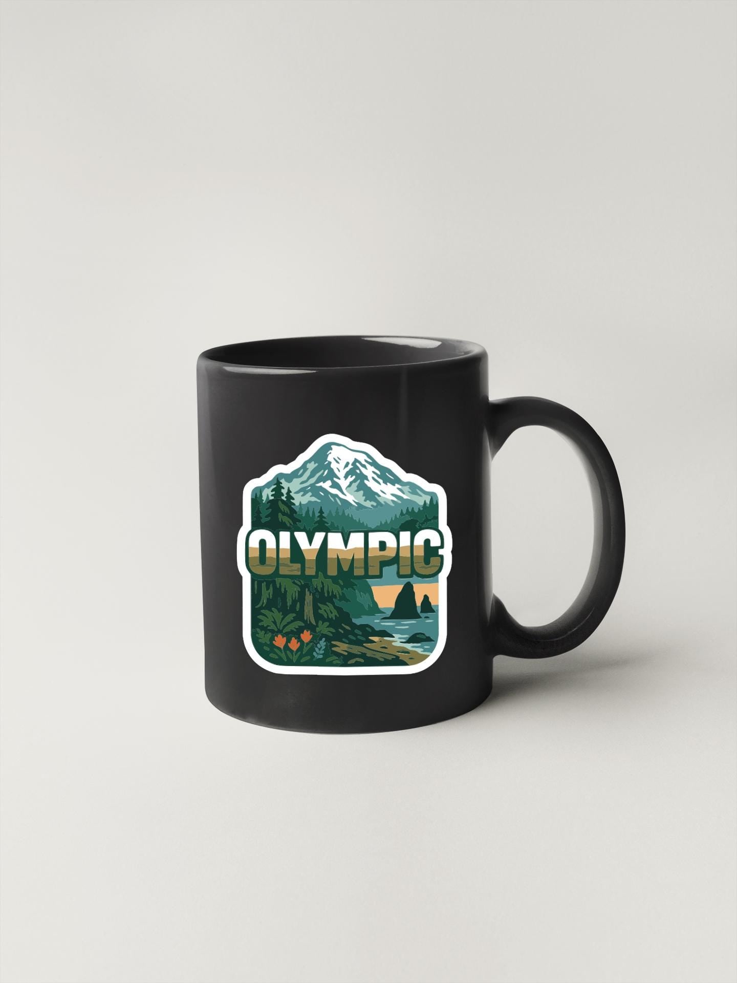 A black coffee mug with a sticker depicting a mountain landscape and the word "OLYMPIC" printed on it.
