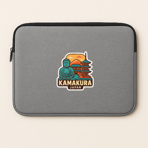 A gray laptop sleeve with a sticker depicting a temple and a Buddha figure, along with the text "KAMAKURA JAPAN".