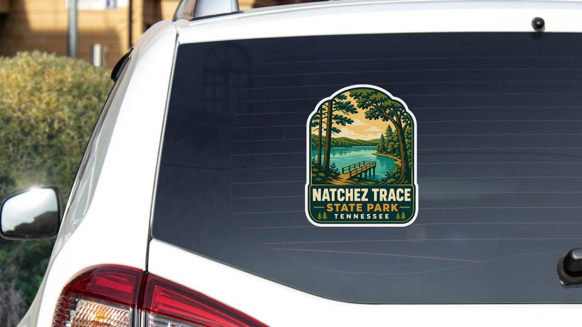 A sticker on the rear window of a white vehicle, depicting a scenic landscape with a lake and a bridge.