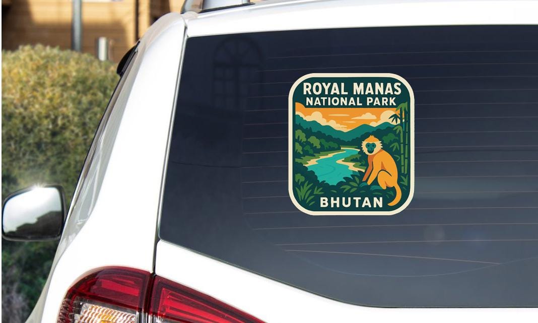 A sticker on the rear window of a car, depicting a scenic landscape with a river, mountains, and a monkey.