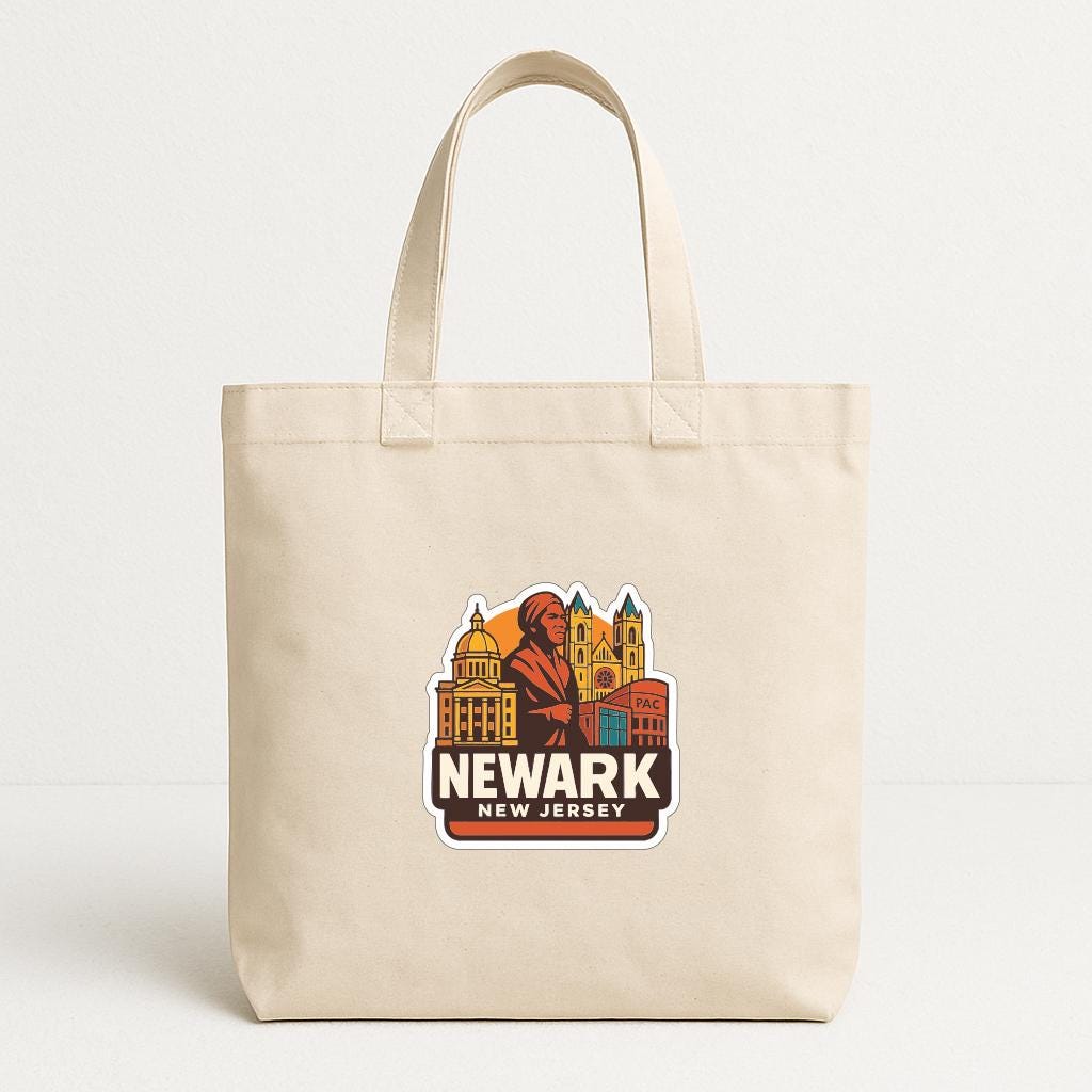 A beige tote bag with a graphic design featuring a stylized illustration of a city skyline and the text "NEWARK NEW JERSEY" printed on it.