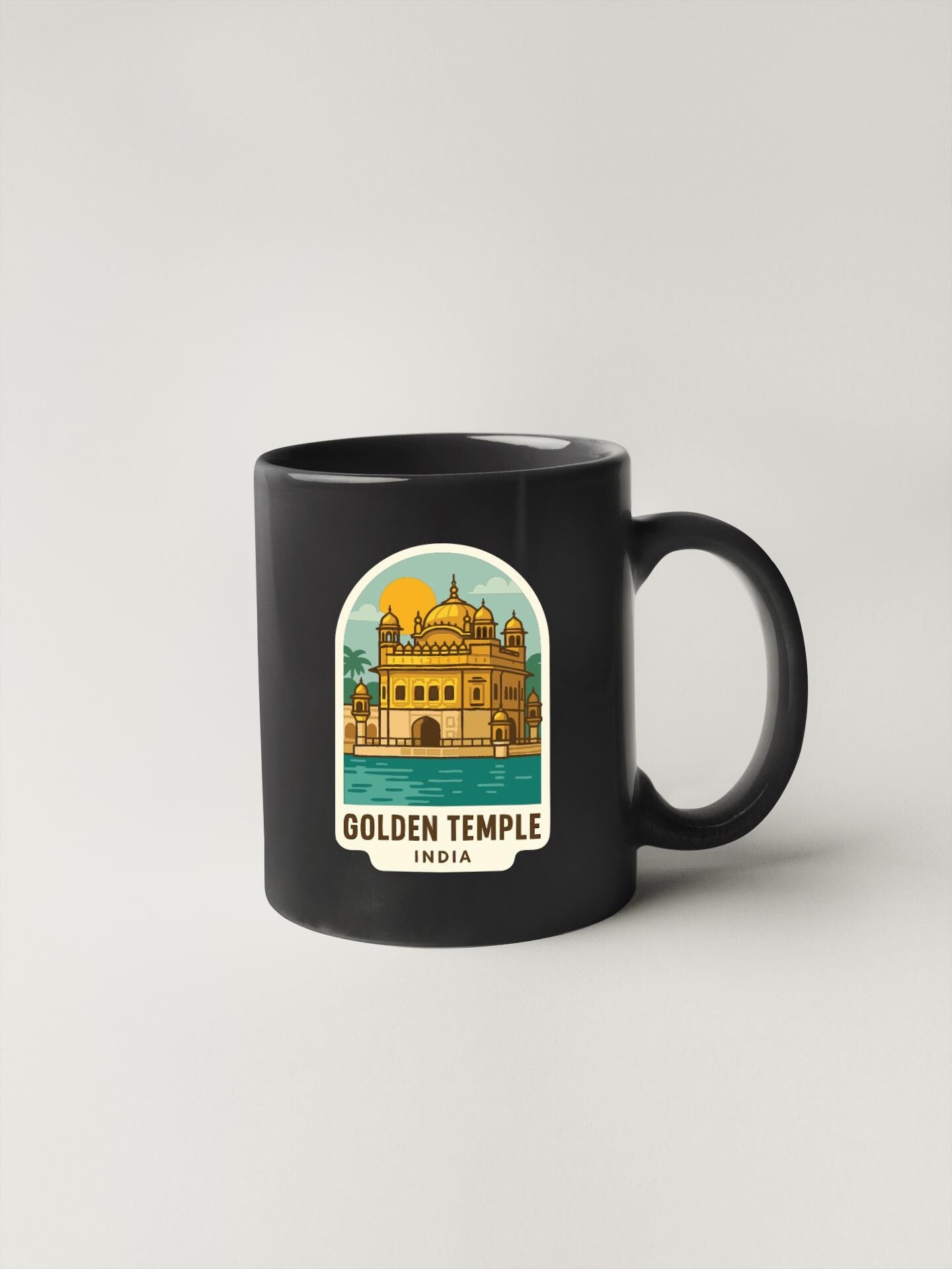 A black coffee mug with a sticker depicting the Golden Temple in India.