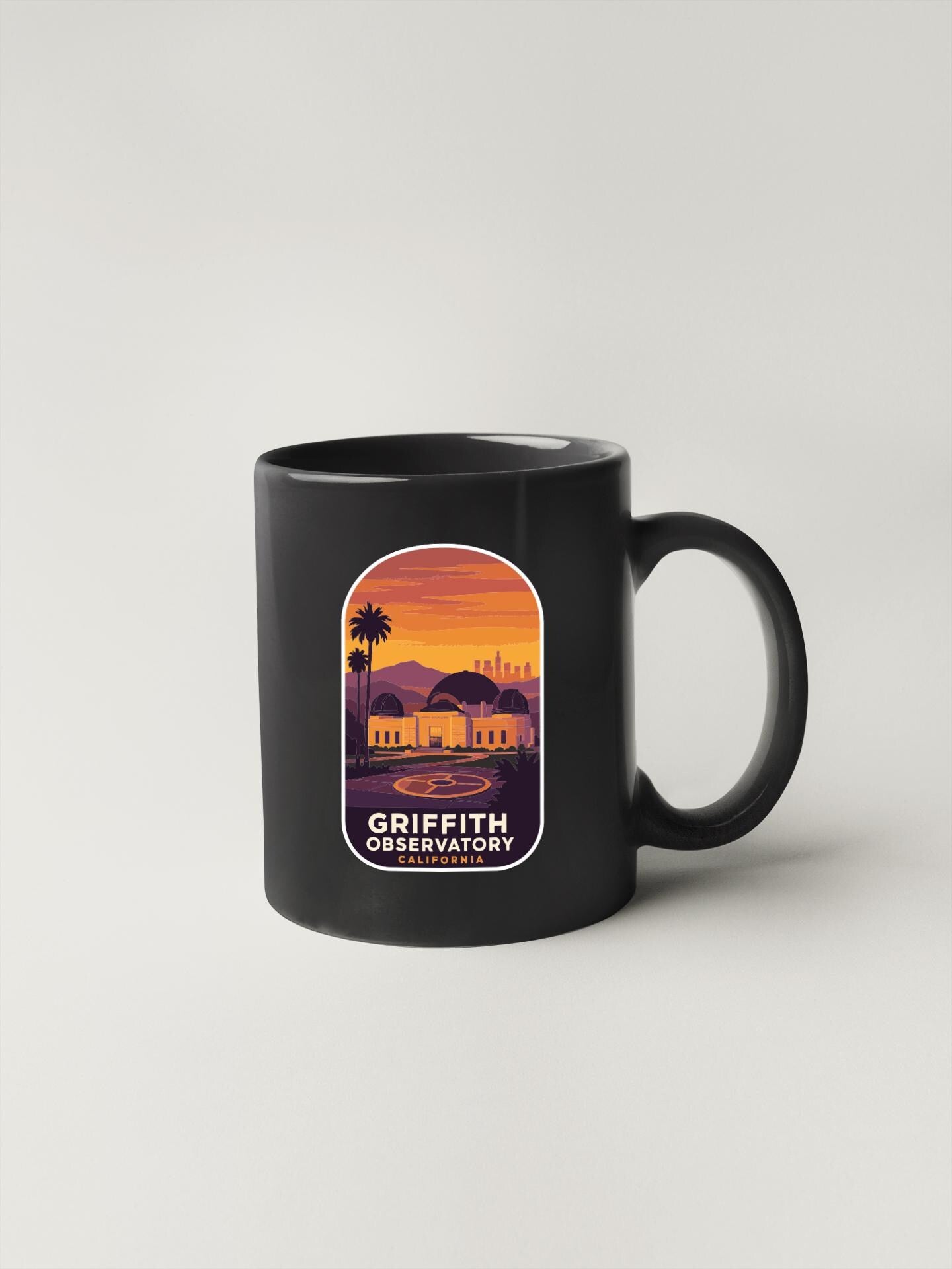 A black coffee mug with a graphic design depicting a sunset over a city skyline.