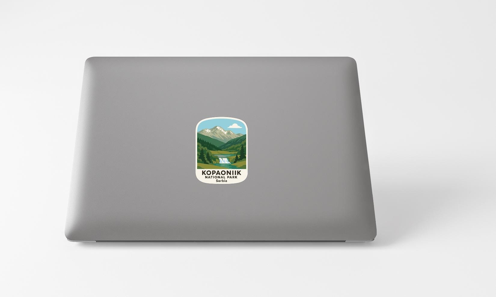 A sticker with a mountain landscape and the text "KOPANIK NATIONAL PARK" printed on a grey laptop.