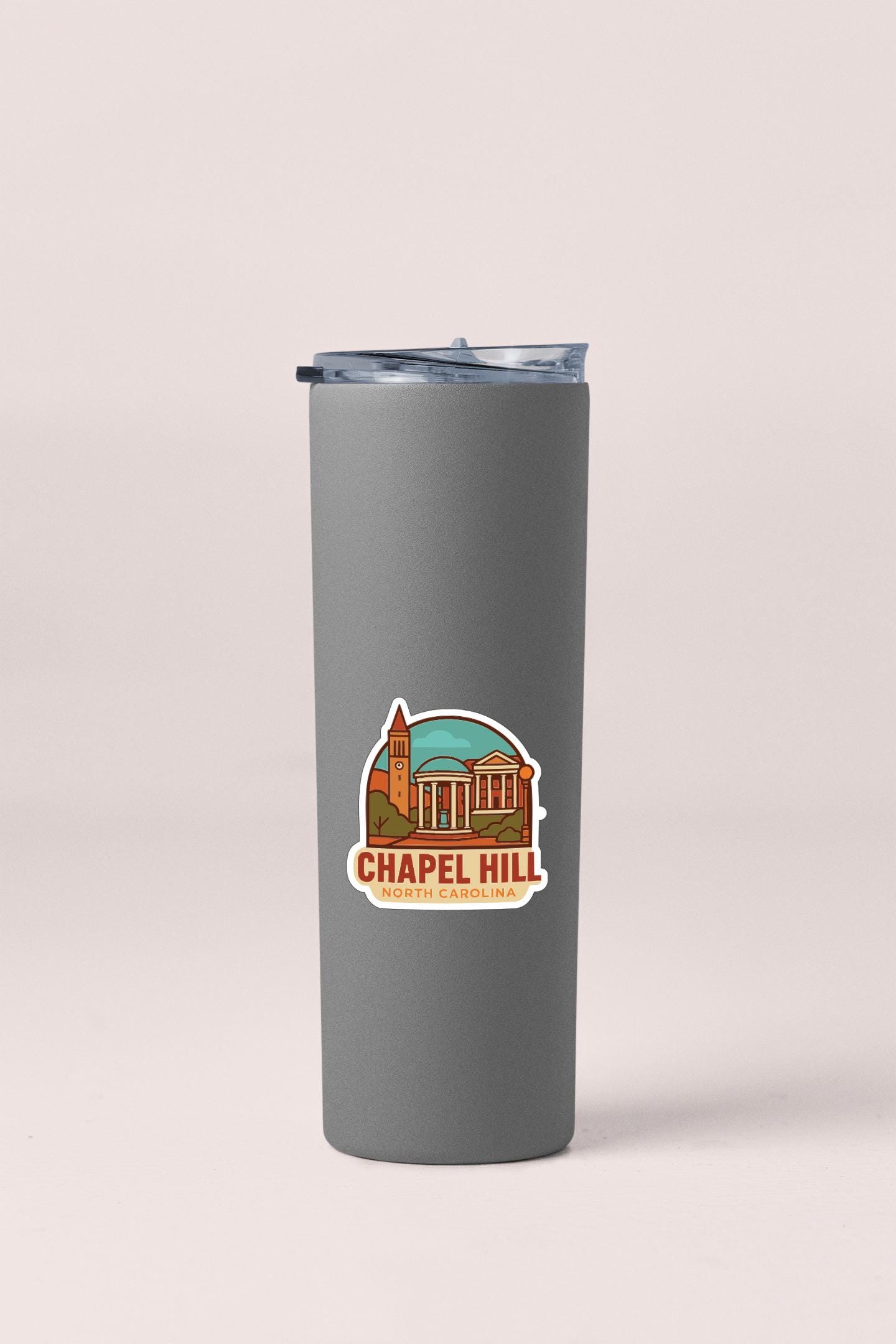 A gray insulated tumbler with a sticker depicting a building and the text "Chapel Hill" printed on it.