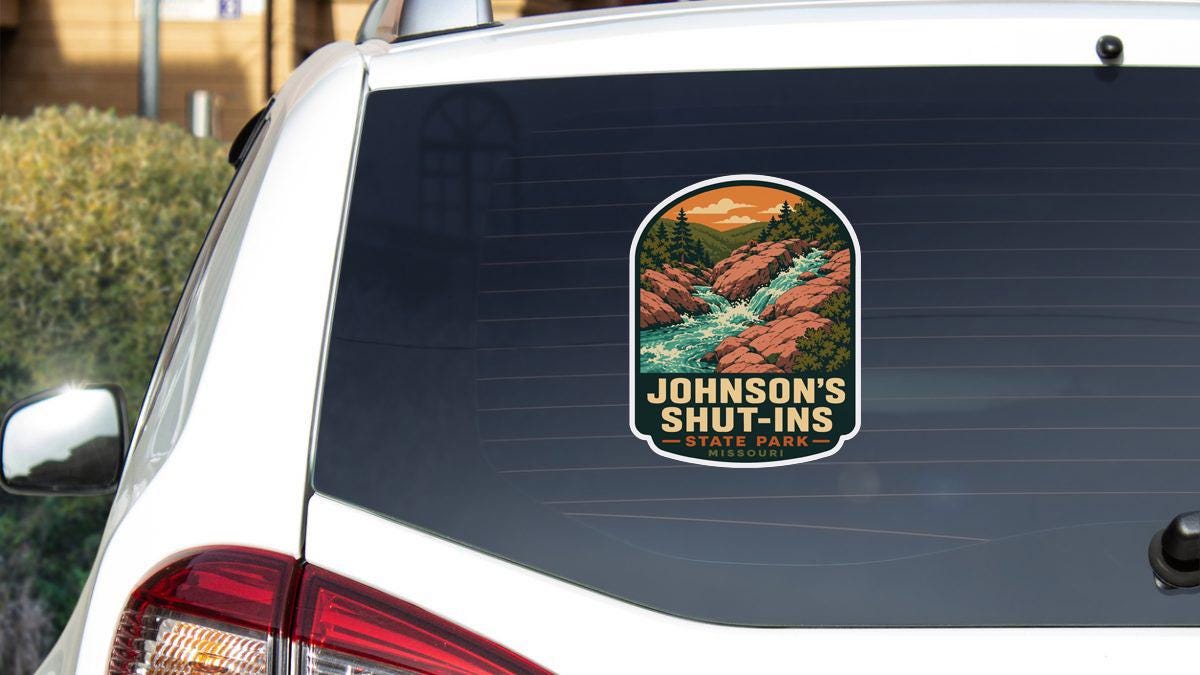 A sticker on the rear window of a white vehicle, depicting a scenic landscape with a river and mountains.