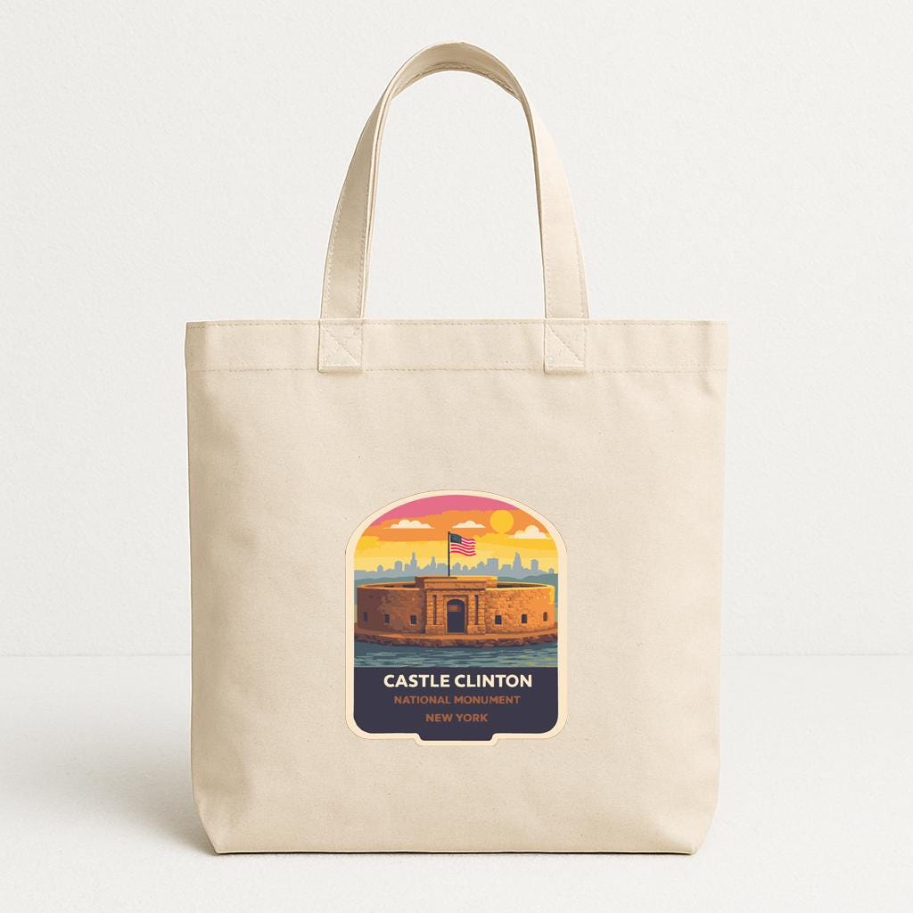 A beige tote bag with a printed label that features an illustration of Castle Clinton, a historic fortification in New York.