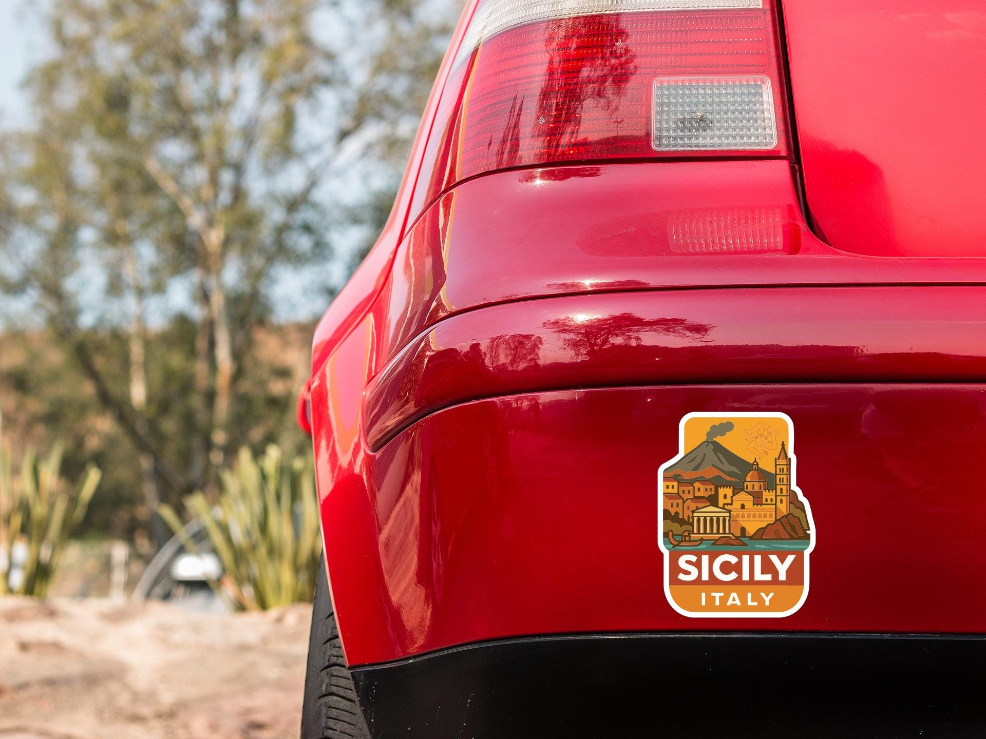 the rear end of a red car with a sticker on the back window that says "SICILY ITALY".