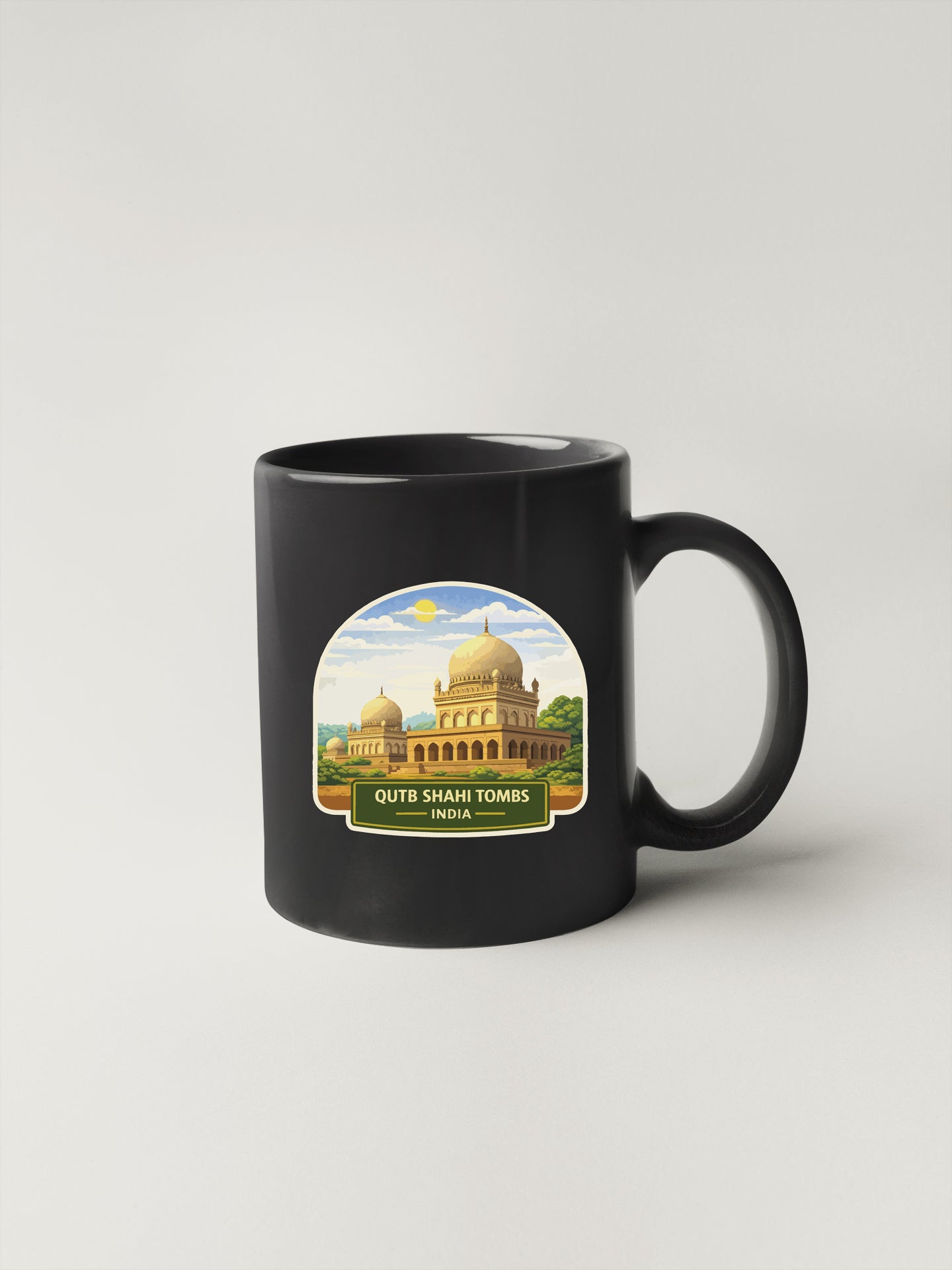 A black coffee mug with a sticker depicting the Qutb Shahi Tombs in India.