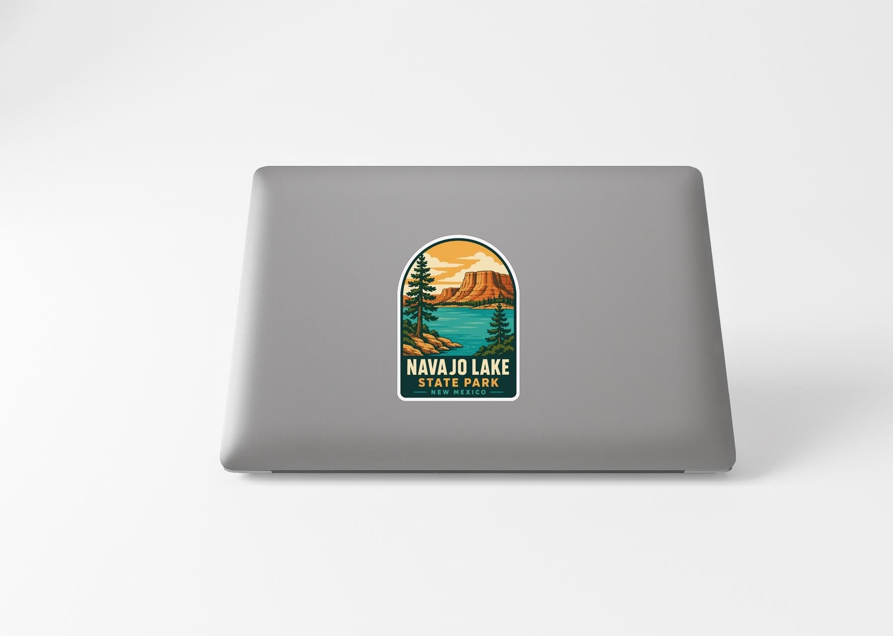 A sticker on the back of a laptop, depicting a scenic landscape with mountains, trees, and a lake.