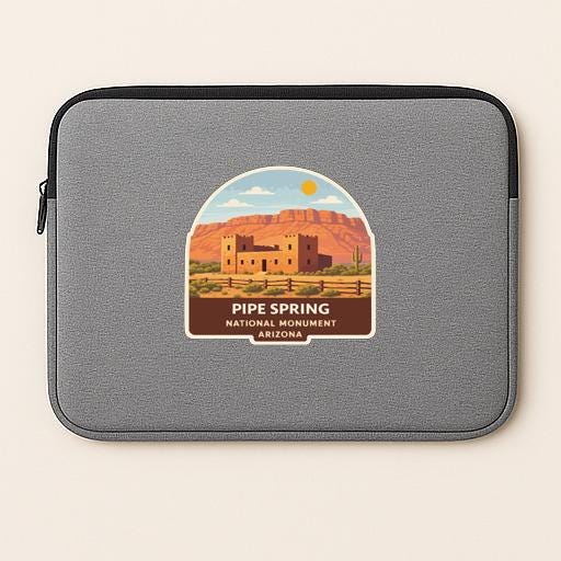 a gray laptop sleeve with a sticker depicting the scenic location of Pipe Spring National Monument in Arizona.