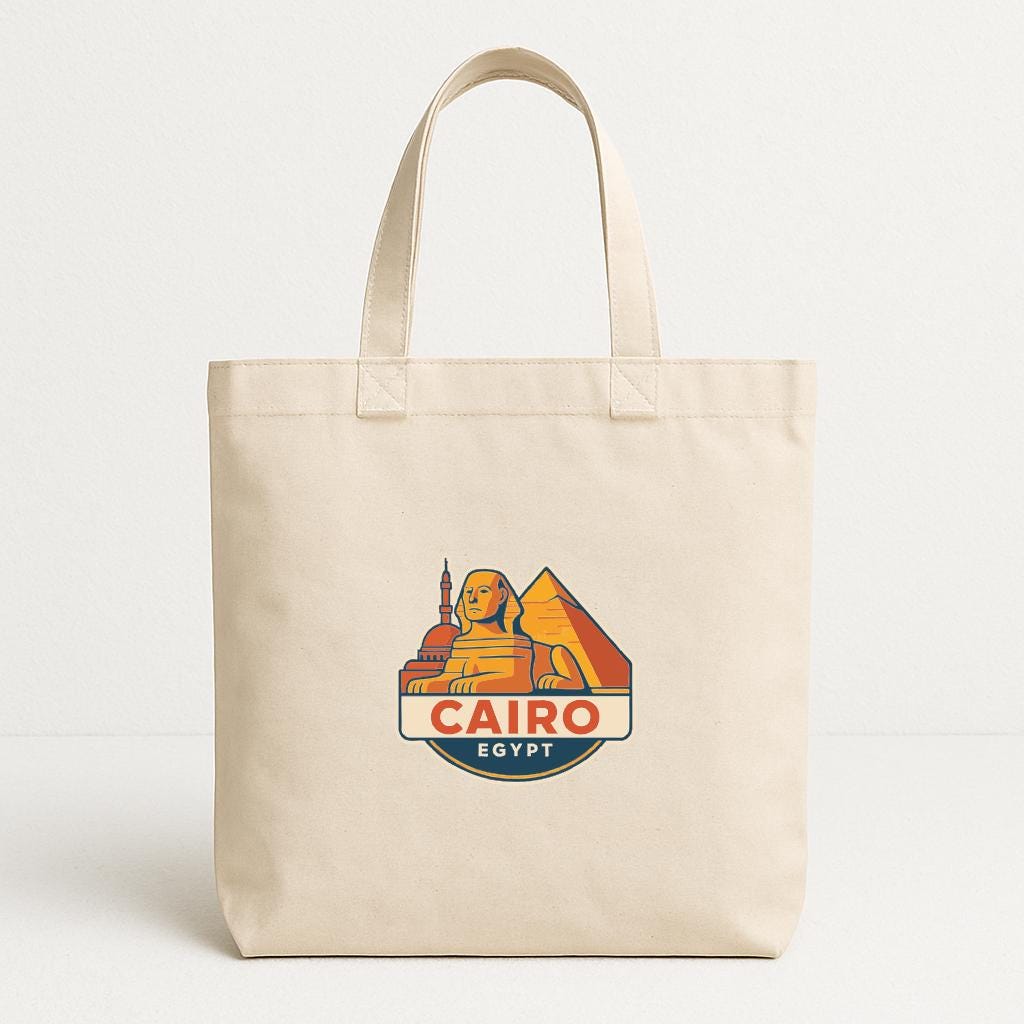 A beige tote bag with a graphic design featuring the city of Cairo, Egypt, including the iconic pyramids and the sphinx.