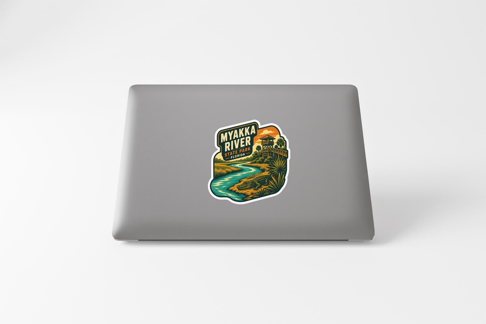 A sticker depicting a scenic view of the Myakka River, with a sunset and landscape in the background.